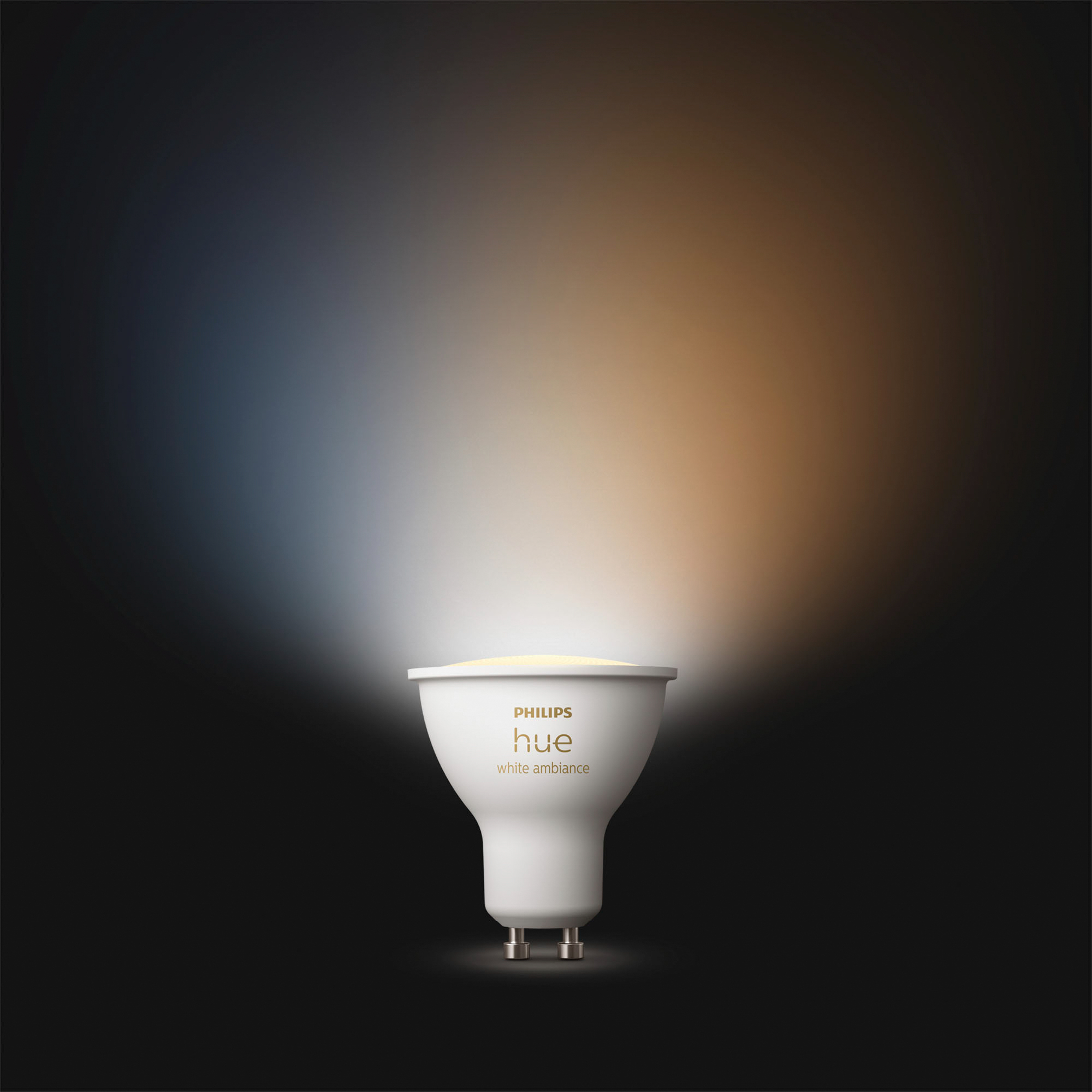 Biała żarówka Philips Hue. Światło jest białe i pomarańczowe. Jest na ciemnym tle.