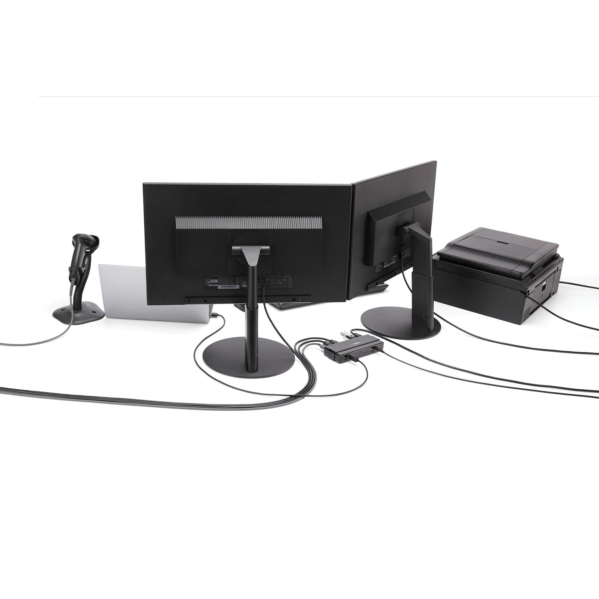 Un setup con due monitor, un laptop e una stampante, collegati da cavi su sfondo bianco.