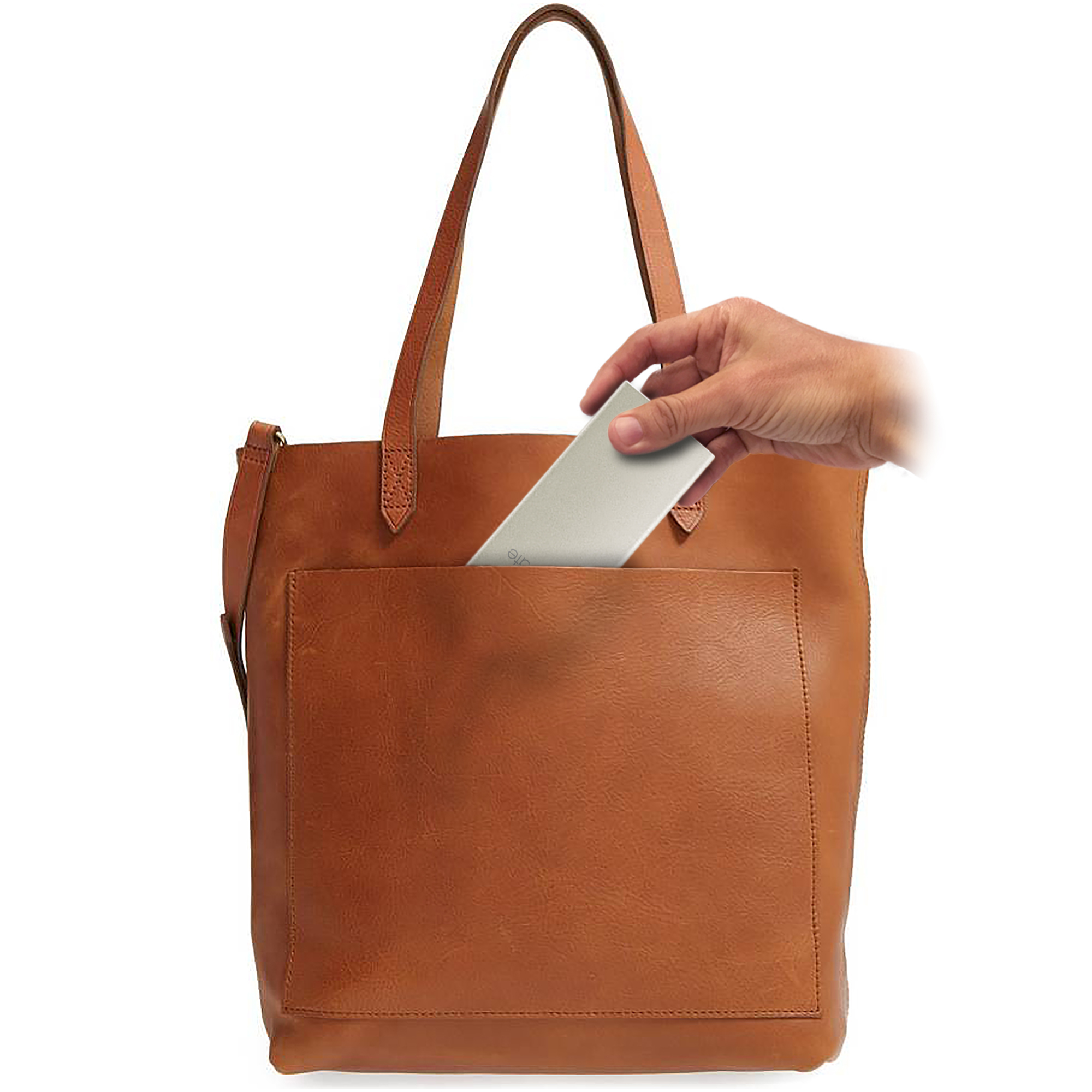 Eine Hand, die einen silbernen Gegenstand in eine braune Ledertasche legt. Die Tasche hat eine Vordertasche.