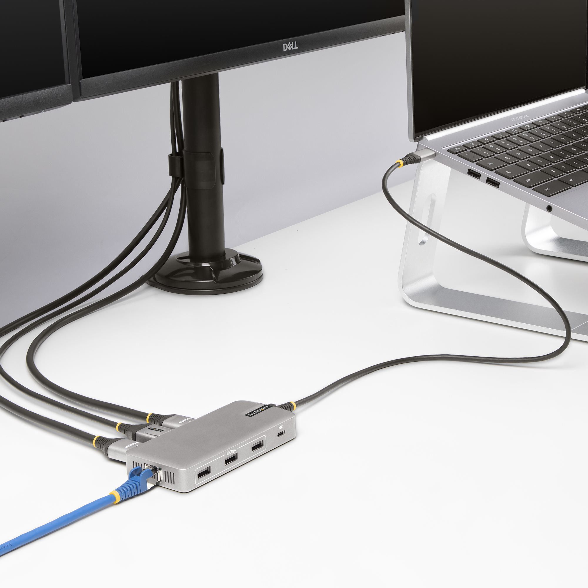Schreibtisch-Setup: Monitore, Laptop und Hub. Kabel verbinden sie. Weißer Schreibtisch.