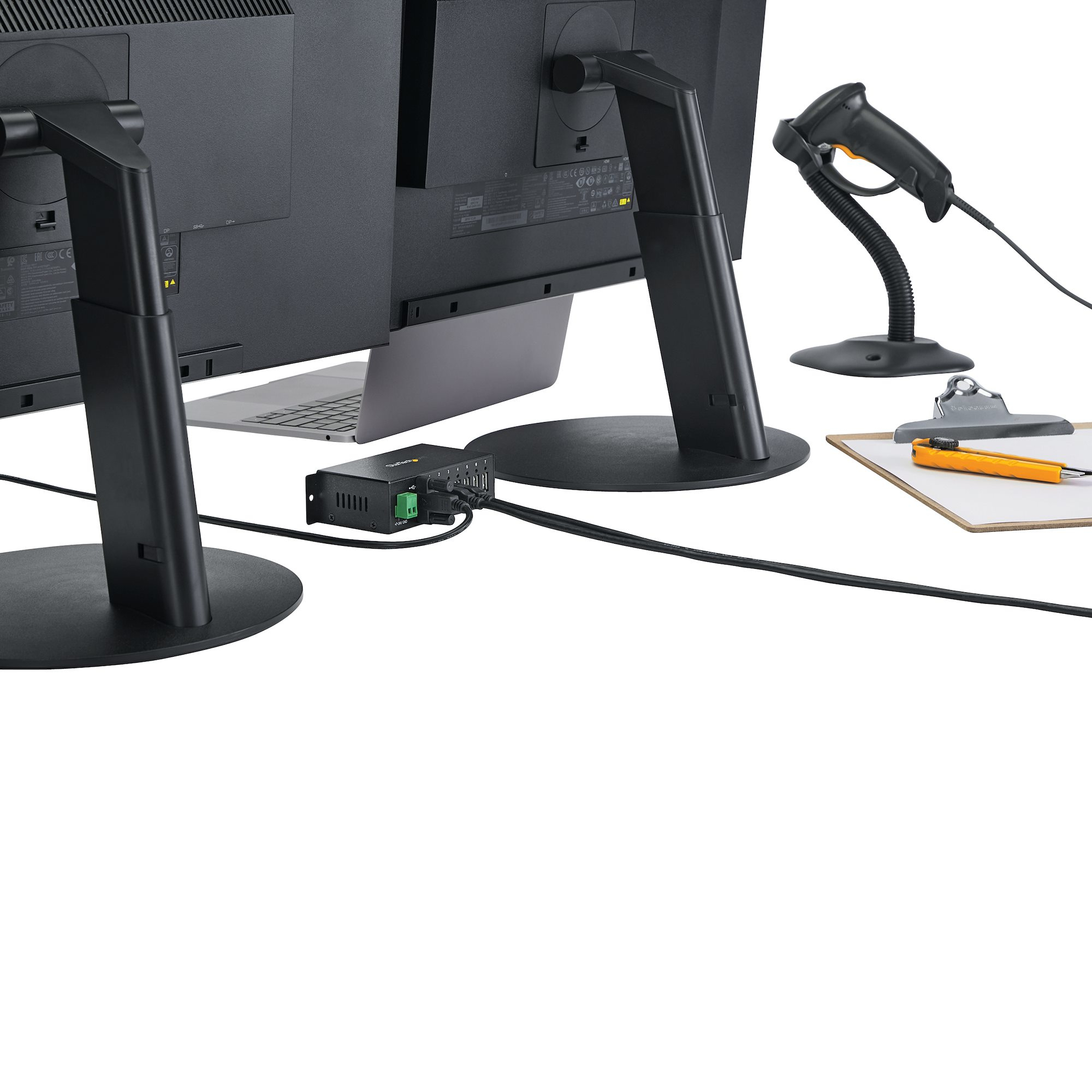 Due monitor di computer, un laptop, uno scanner, un blocco appunti e un cavo nero su una scrivania bianca.