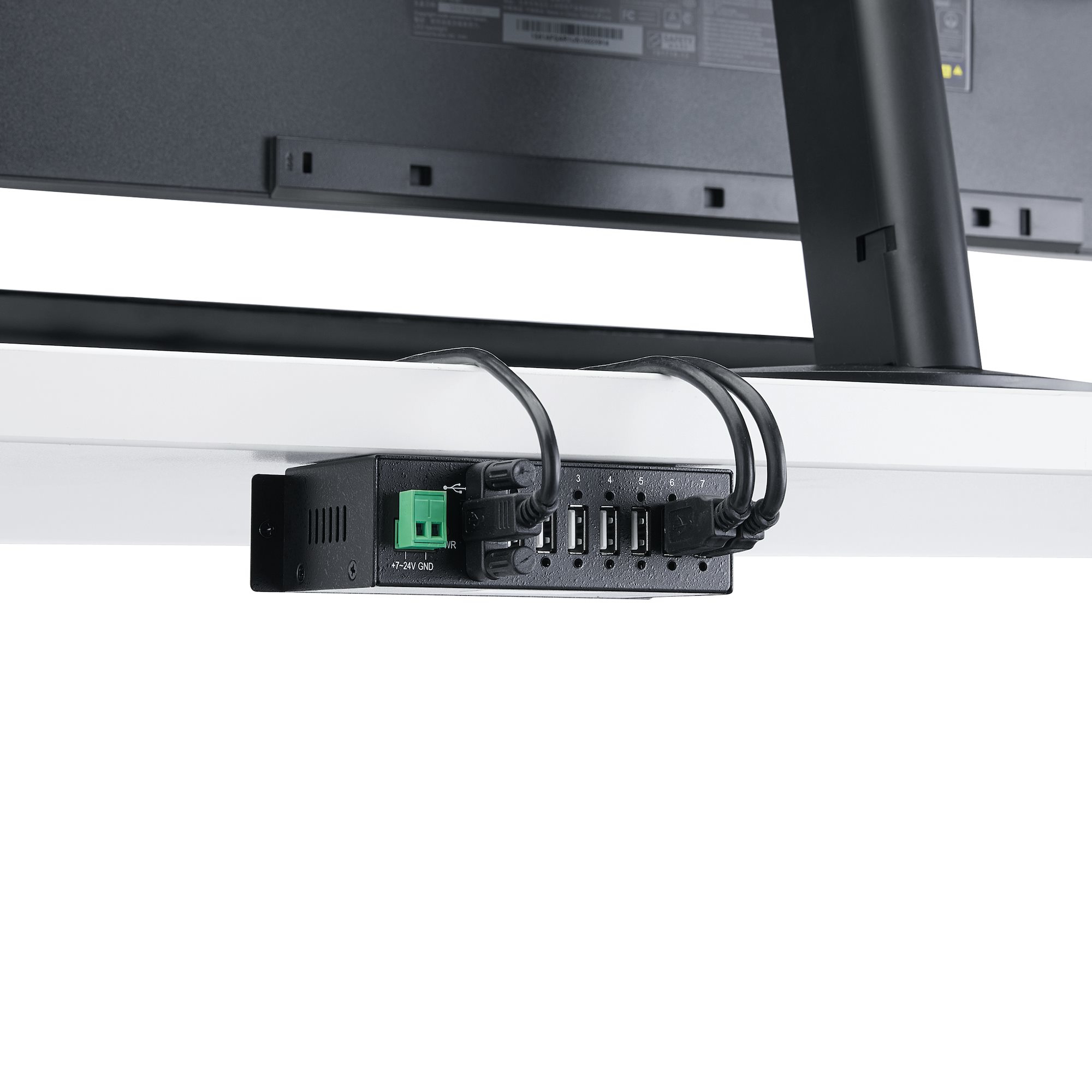 Hub USB nero con più porte, fissato sotto una scrivania, monitor sullo sfondo.