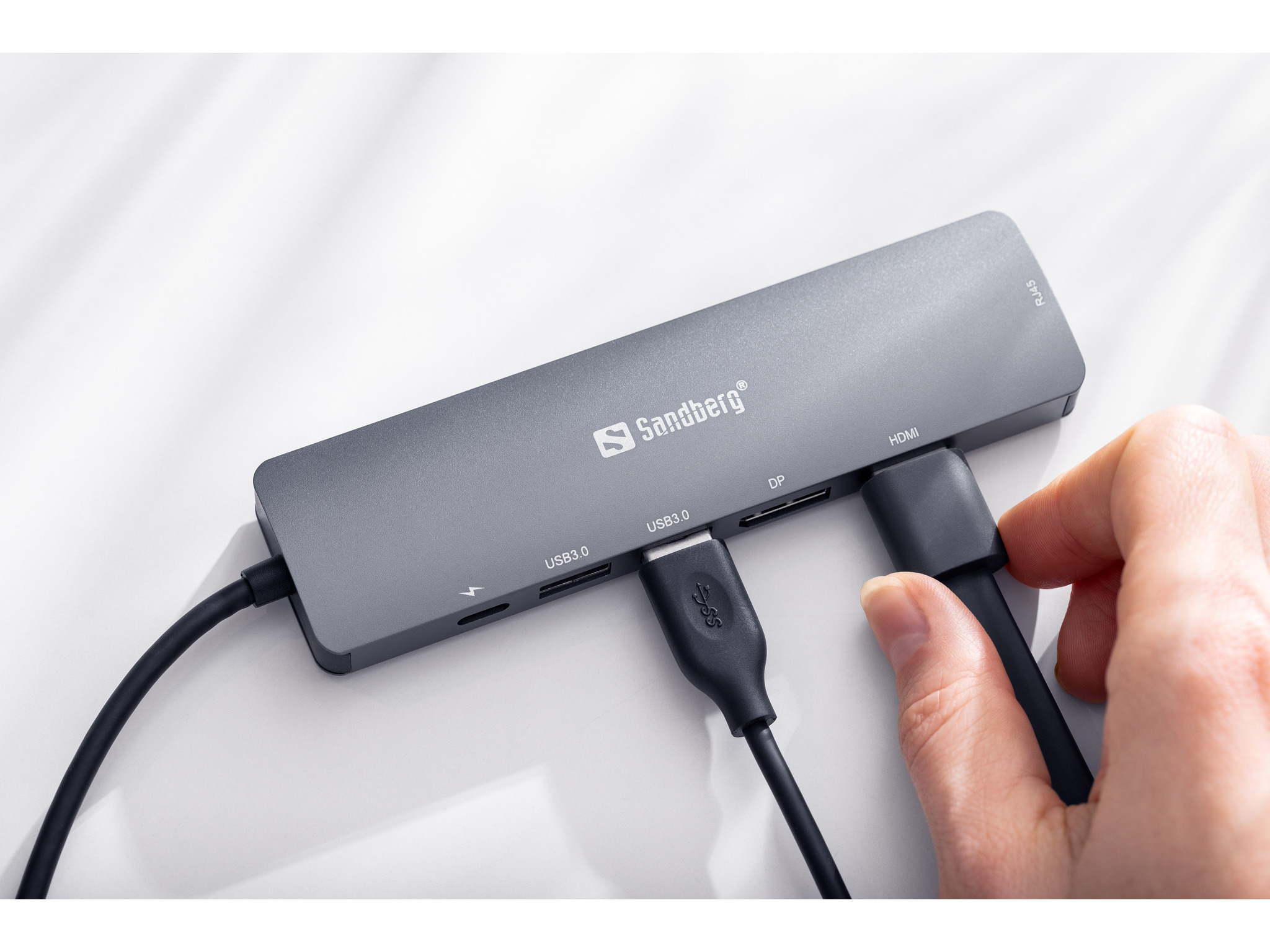 Ein grauer UGREEN-Hub mit mehreren Anschlüssen und angeschlossenen Kabeln, einschließlich USB und HDMI.