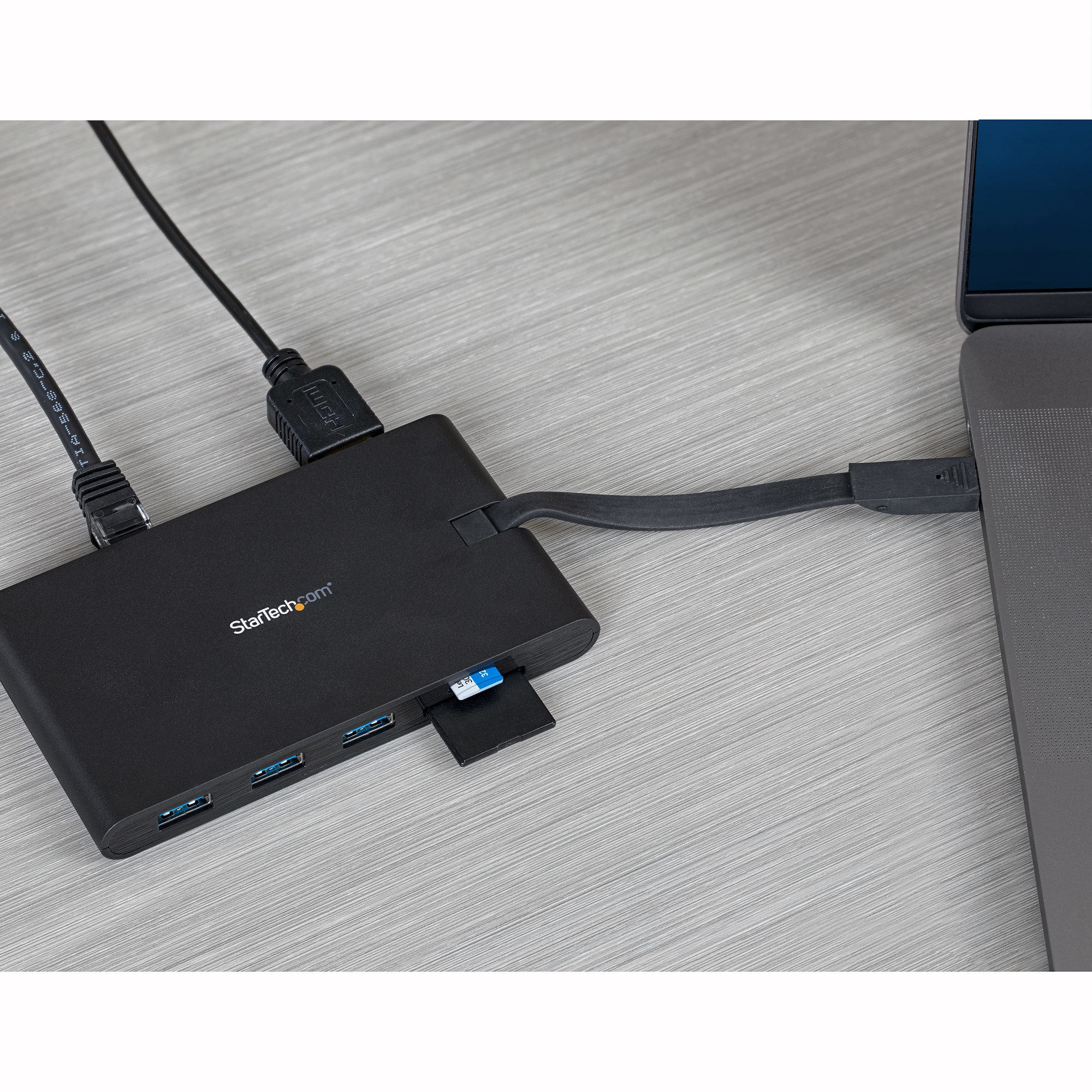 Un hub USB nero con porte, collegato a un laptop. Inserita una scheda SD.