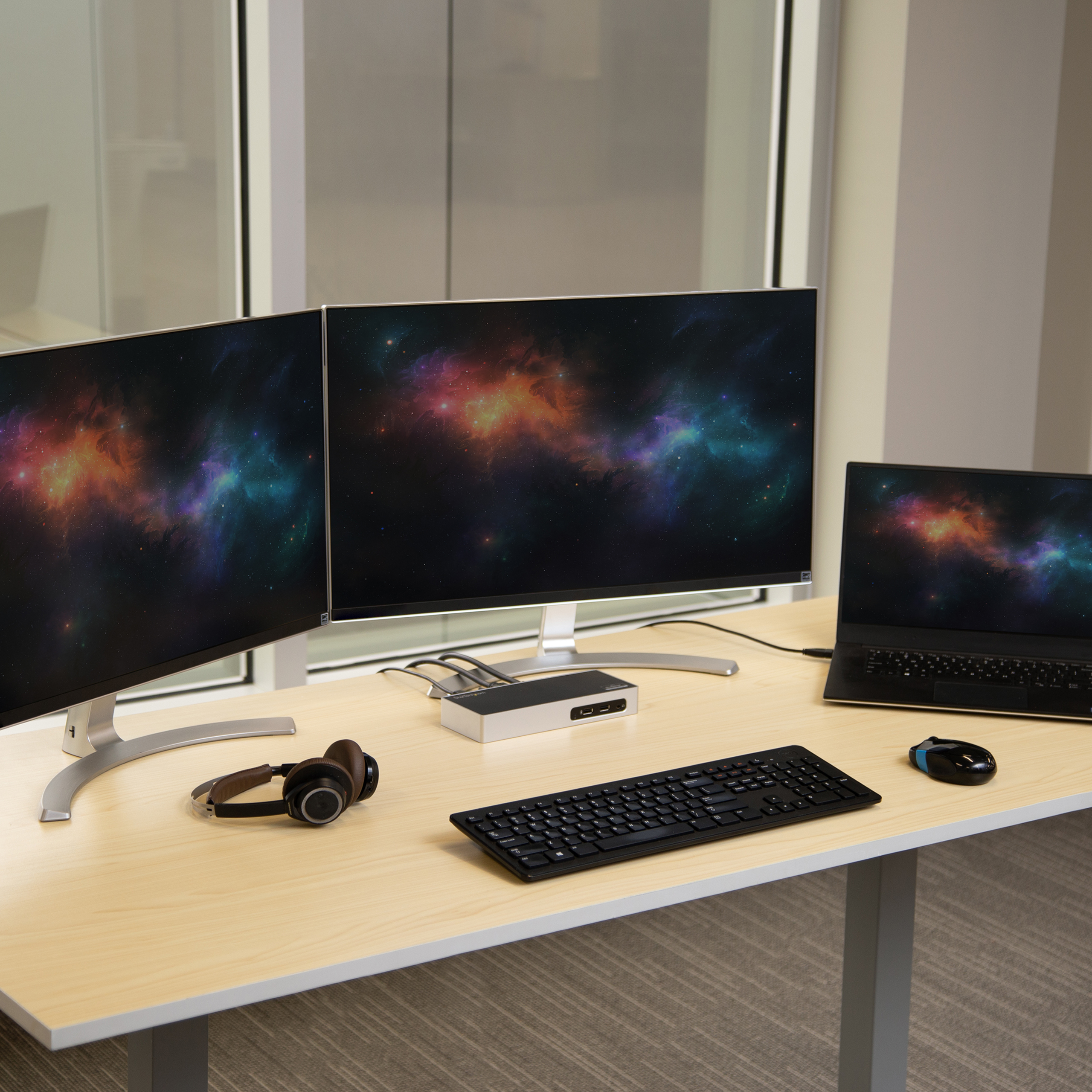 Un setup da scrivania con due monitor, un laptop e un hub. Sono visibili una tastiera e un mouse.