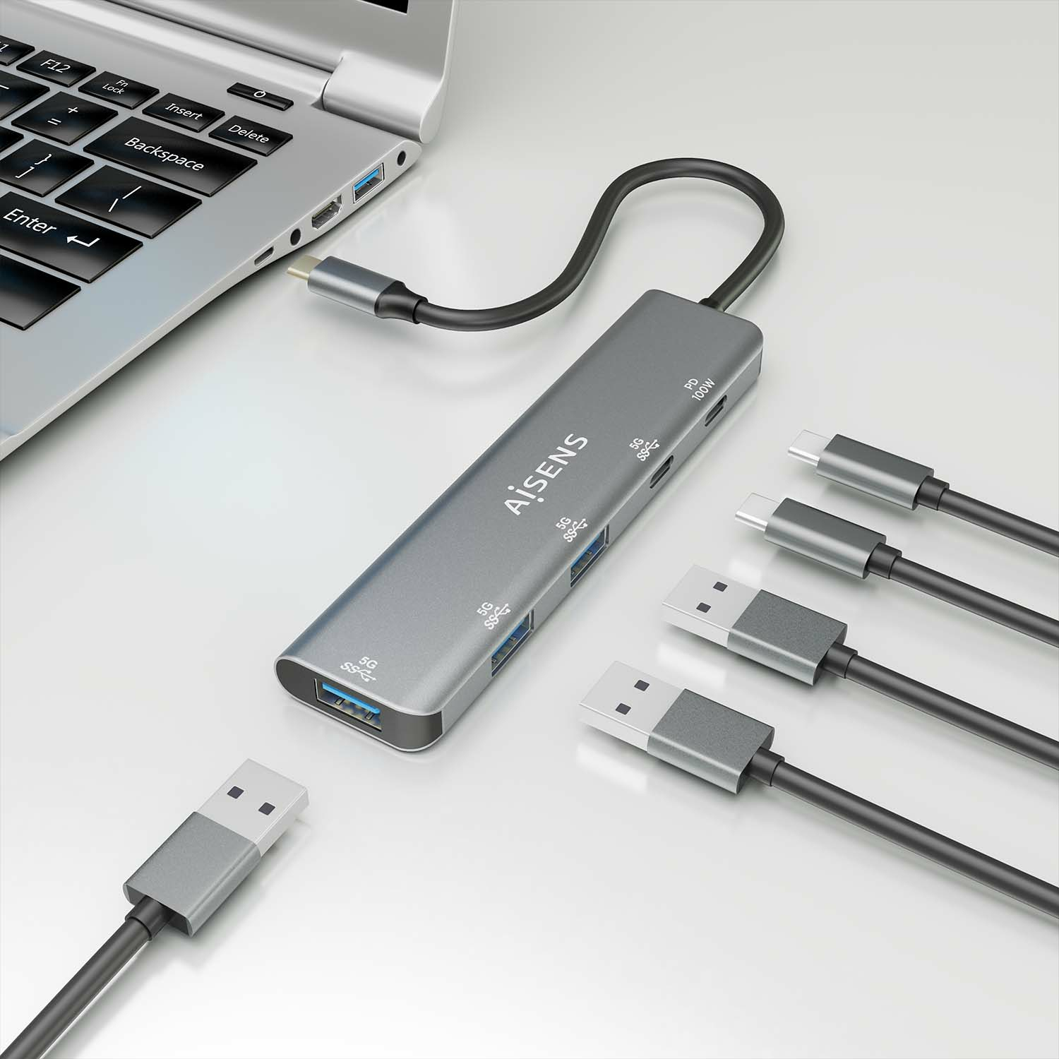 Hub argentato collegato a un laptop con più cavi USB.