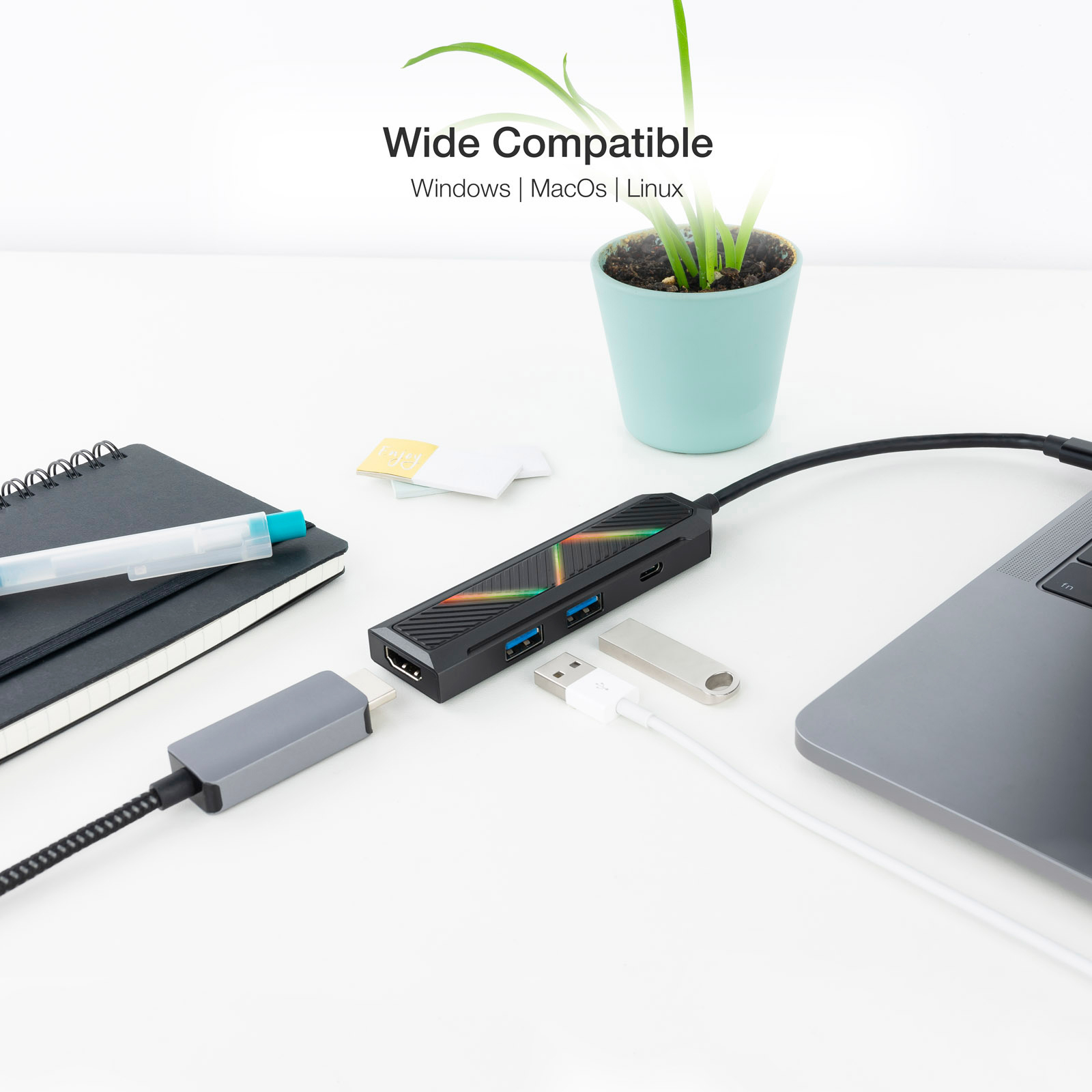 Un concentrador USB con múltiples puertos, conectado a una laptop. Hay un bolígrafo y un cuaderno.
