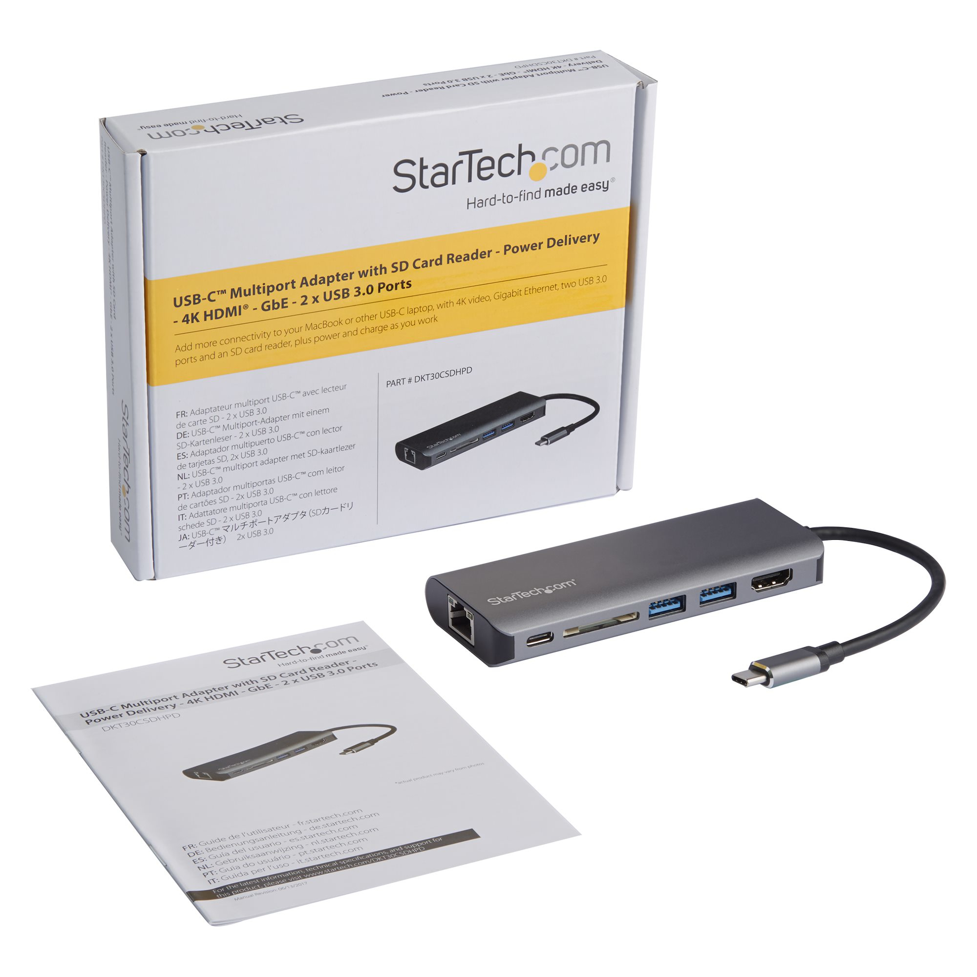 Un adattatore multiporta USB-C con una scatola e dei fogli su una superficie bianca.
