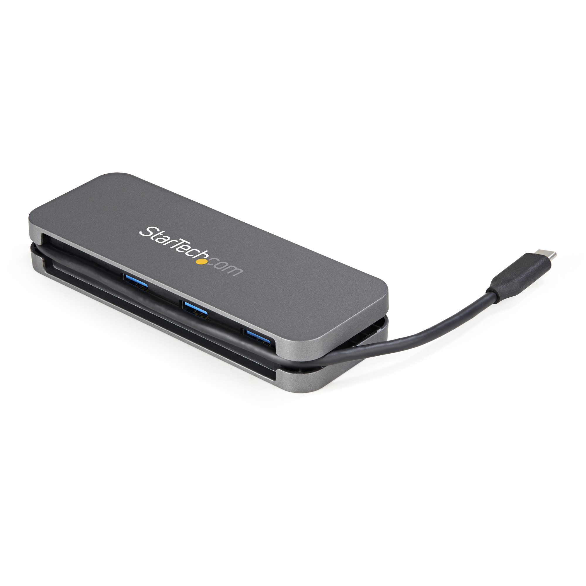 Un hub USB-C gris con múltiples puertos, en ángulo sobre superficie blanca con cable negro.