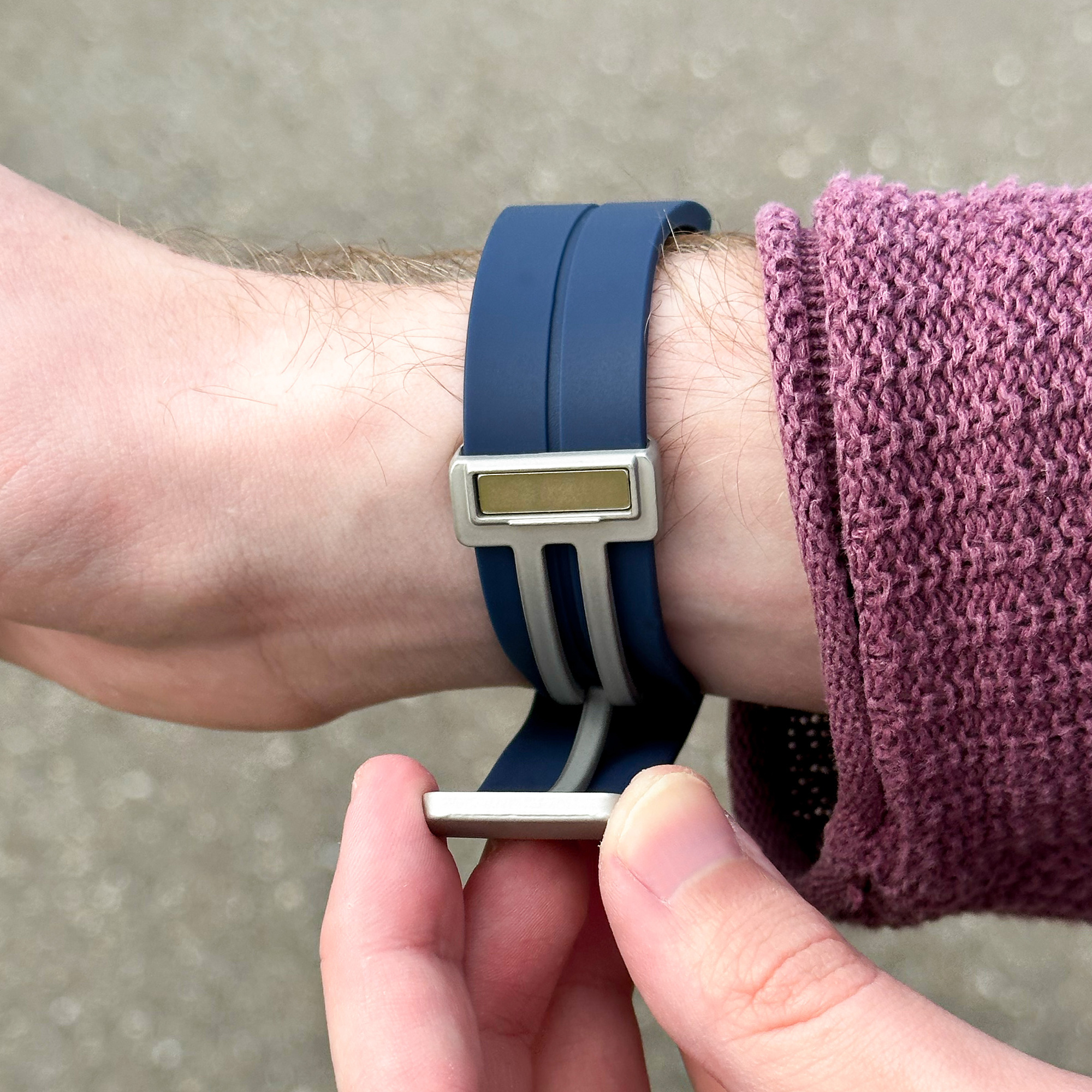 Hand einer Person mit blau-silbernem Armbanduhr am Handgelenk.