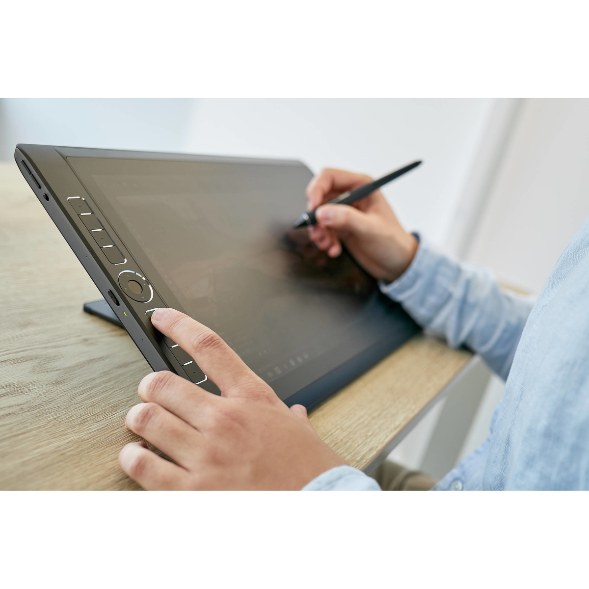 Person zeichnet mit einem Stift auf einem schwarzen digitalen Tablet. Das Tablet steht schräg auf einem Ständer.