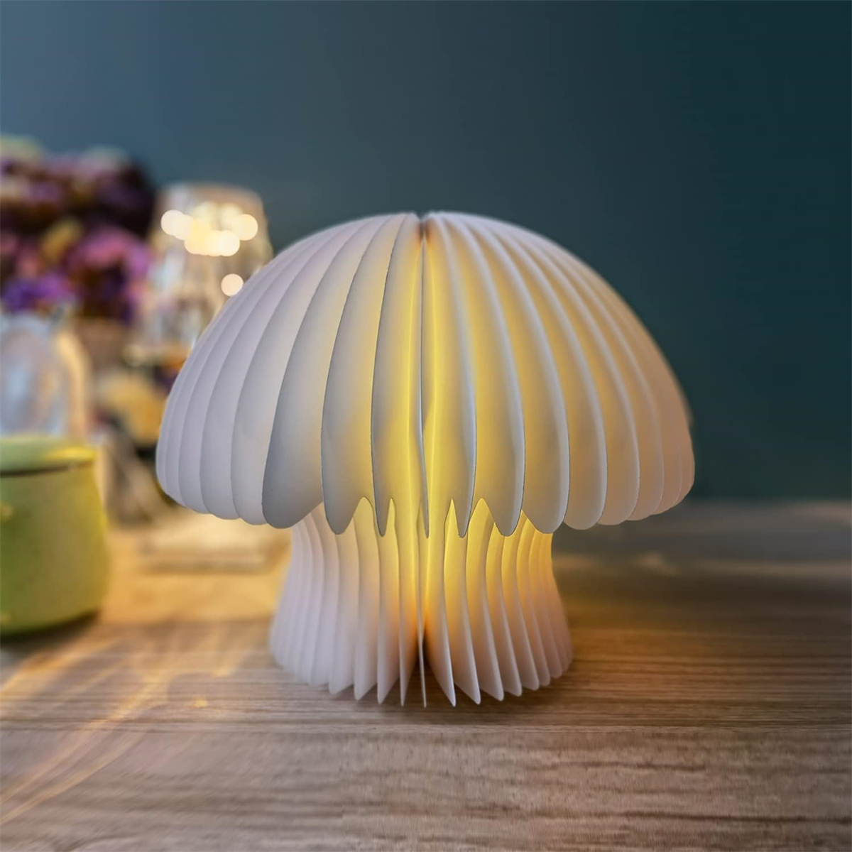Eine pilzförmige Lampe aus weißem, geschichtetem Papier, von innen beleuchtet, auf einem Holztisch.