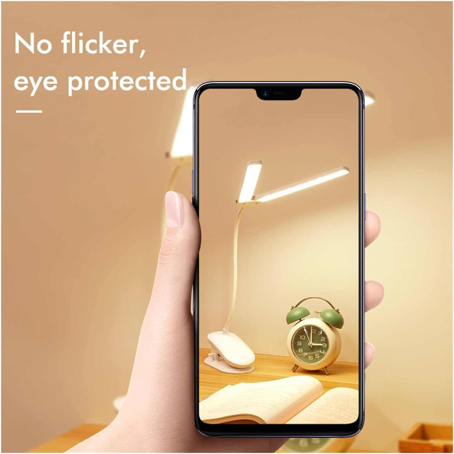 Eine Hand, die ein Telefon hält, das eine Schreibtischlampe, einen Wecker und ein Buch zeigt.