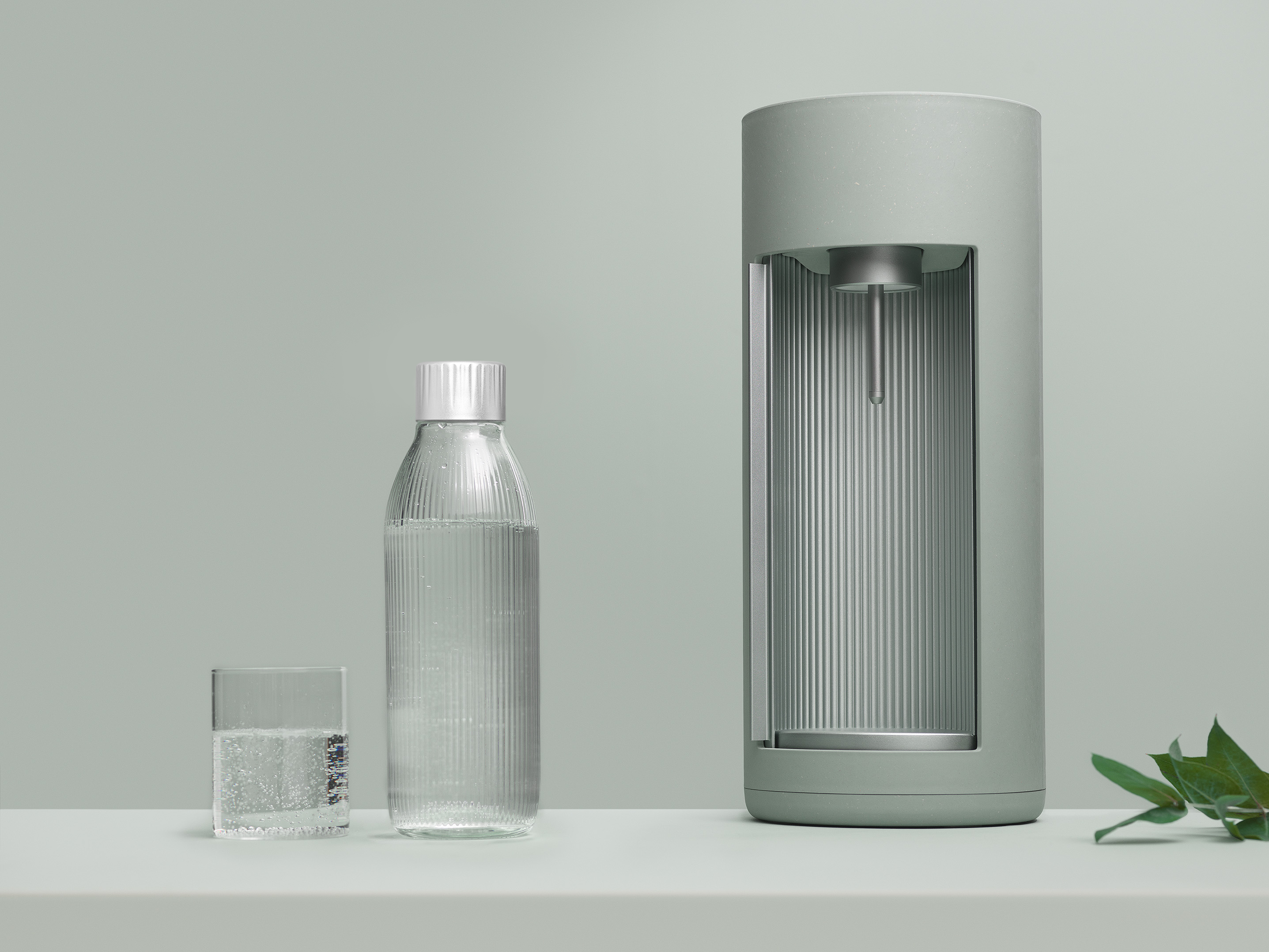 Groene en zilveren waterdispenser, glas en fles op een wit oppervlak.