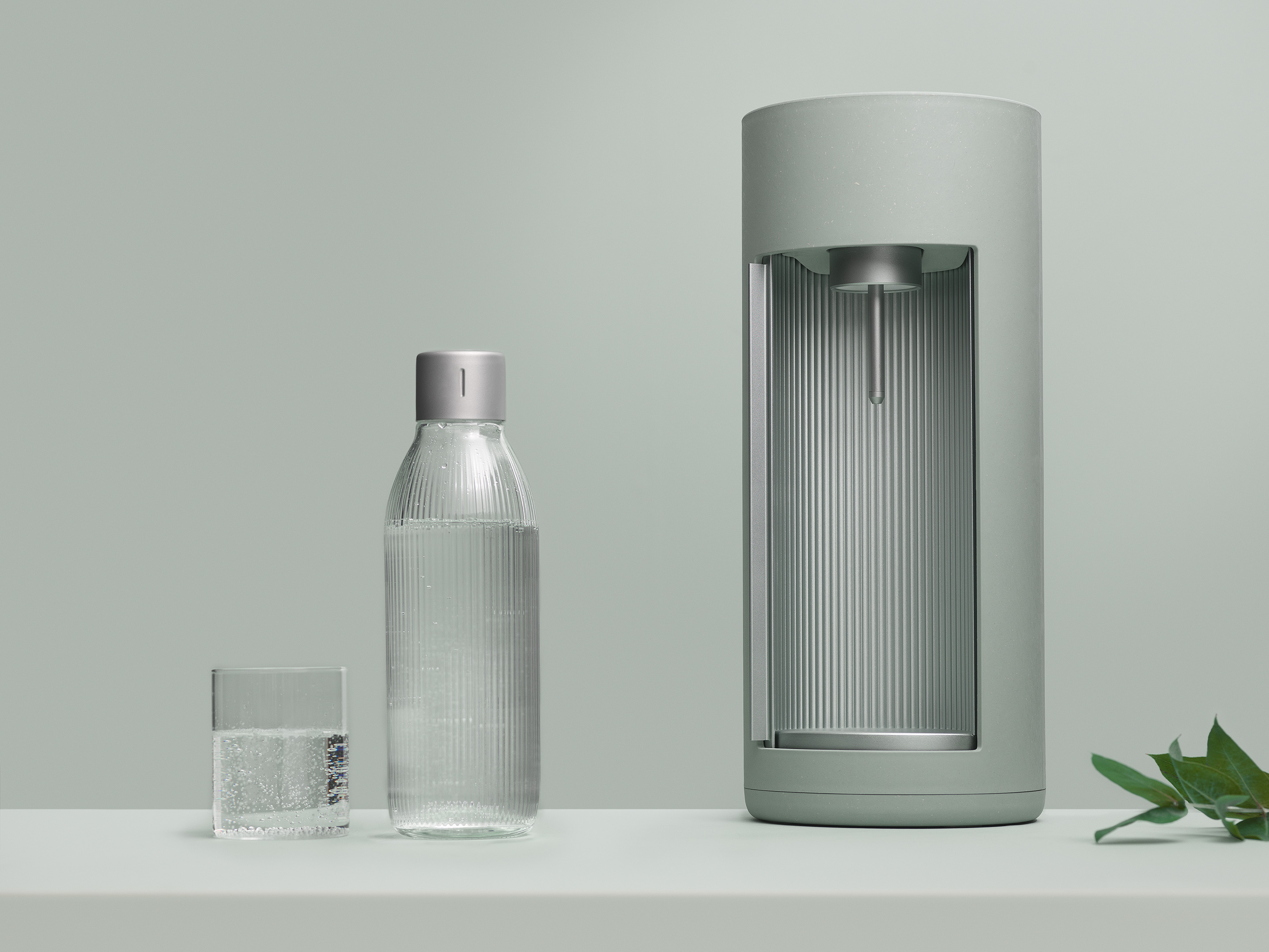 Sodamaker met accessoires. Groene sodamaker, glas, fles op wit oppervlak.