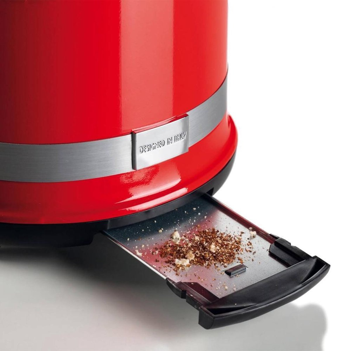 Red toaster with crumbs in the tray. Designed in Italy label visible.