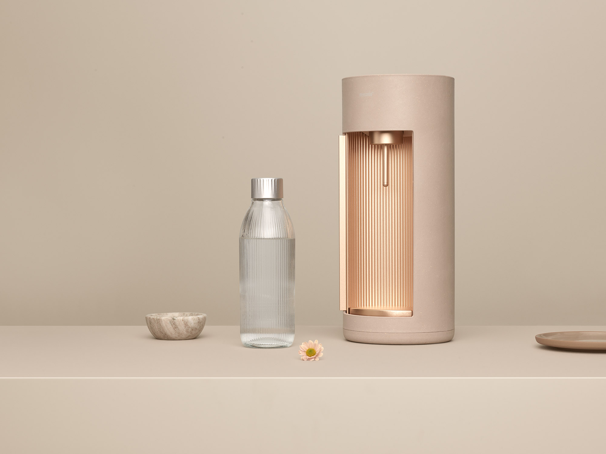 Een waterdispenser en een glazen fles. Een waterfles en een kleine kom staan naast de dispenser.