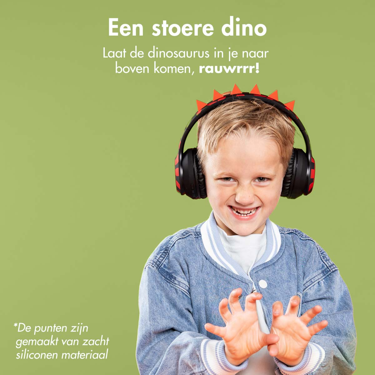 Jonge jongen met een spijkerjasje en dinosaurus koptelefoon die lacht. Groene achtergrond.