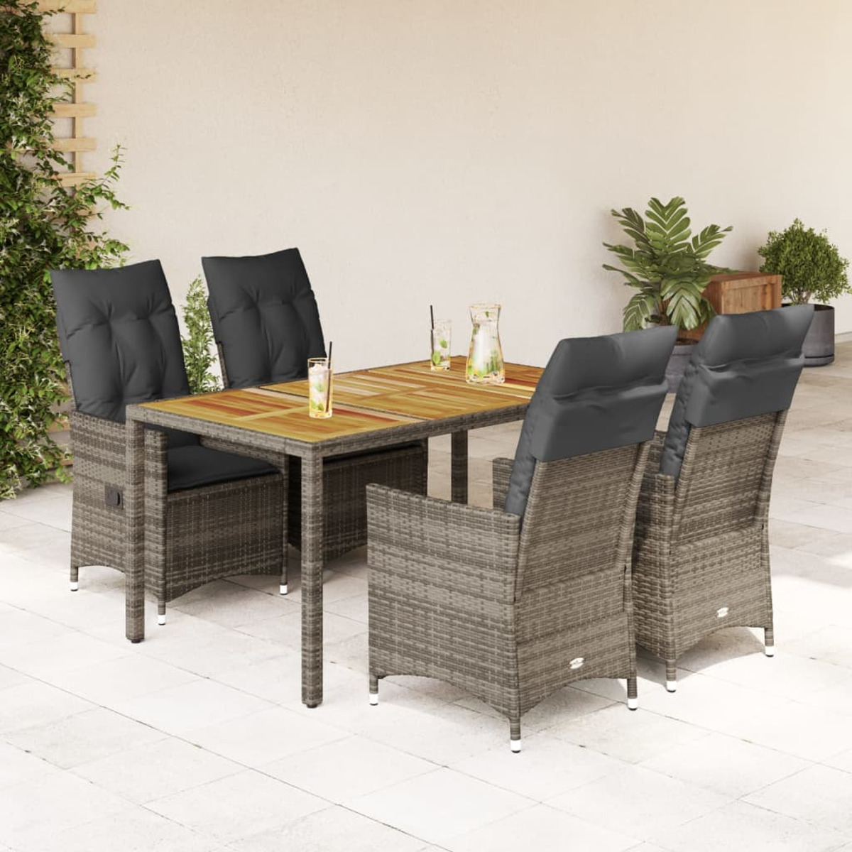Essgruppe aus Rattan. Tisch mit Getränken, vier Stühle mit Kissen. Hintergrund ist Terrasse.