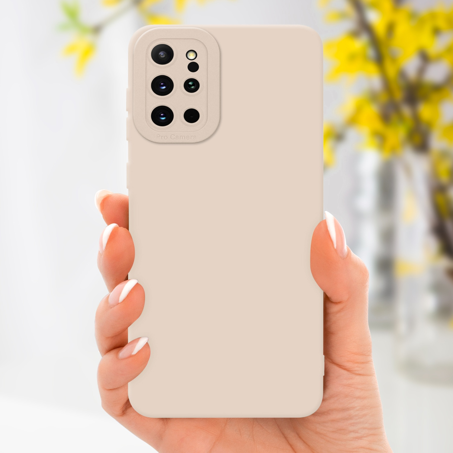 Une main tenant un étui de téléphone beige avec une découpe pour l'appareil photo, des fleurs jaunes en arrière-plan.