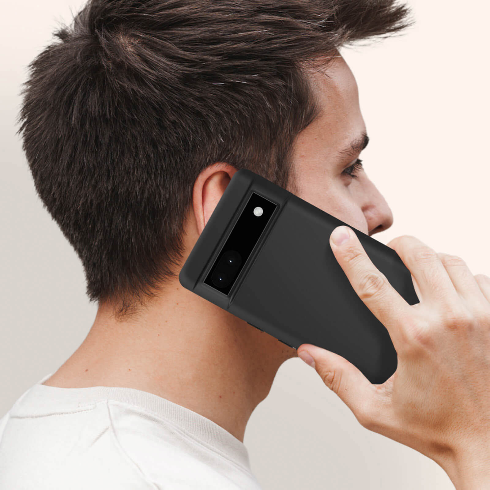 Persona che tiene un telefono nero all'orecchio. Il telefono ha un rigonfiamento della fotocamera.