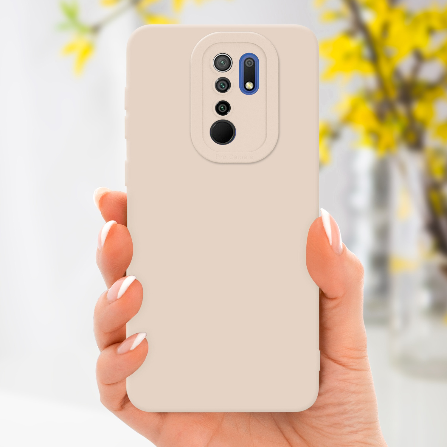 Una mano che tiene una custodia beige per telefono con più ritagli per fotocamera, con fiori gialli sfocati sullo sfondo.