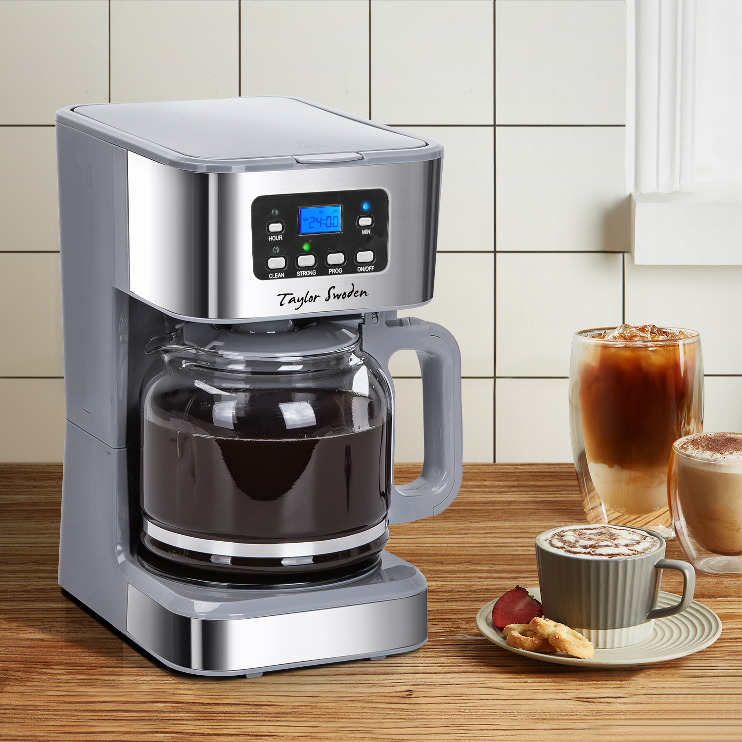 Una macchina per il caffè grigia con display digitale, con bevande al caffè e biscotti nelle vicinanze.