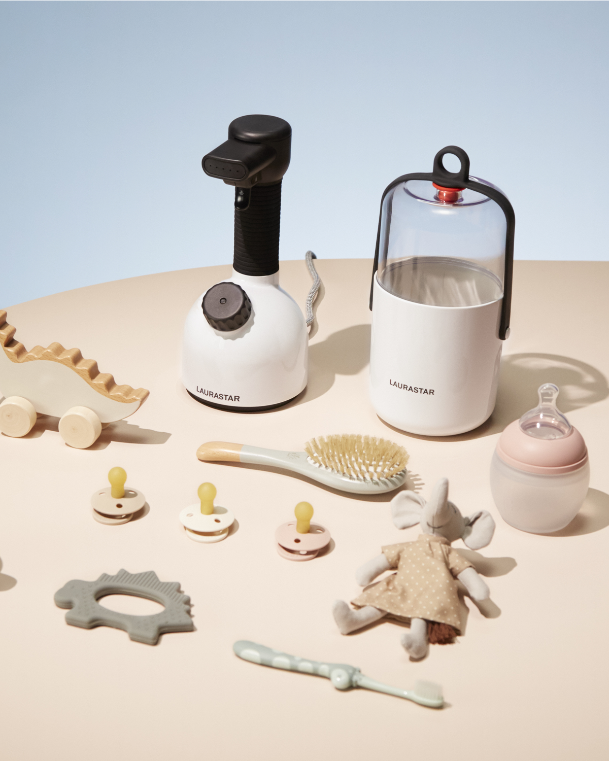 Eine Sammlung von Babyartikeln: Dampfer, Flasche, Schnuller, Bürste und Spielzeug.