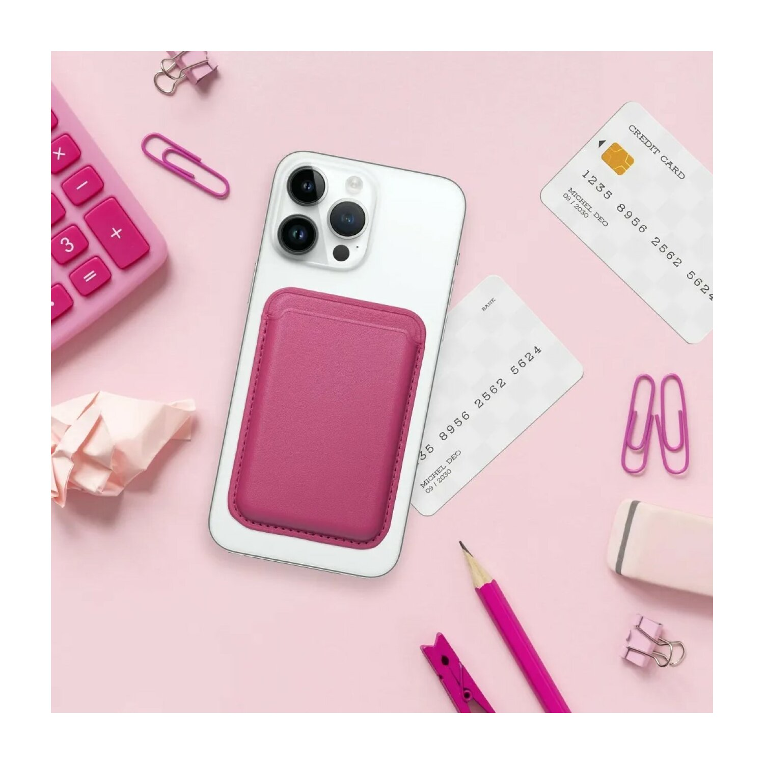 Telefono con porta carte magenta, carte di credito e forniture per ufficio su rosa.