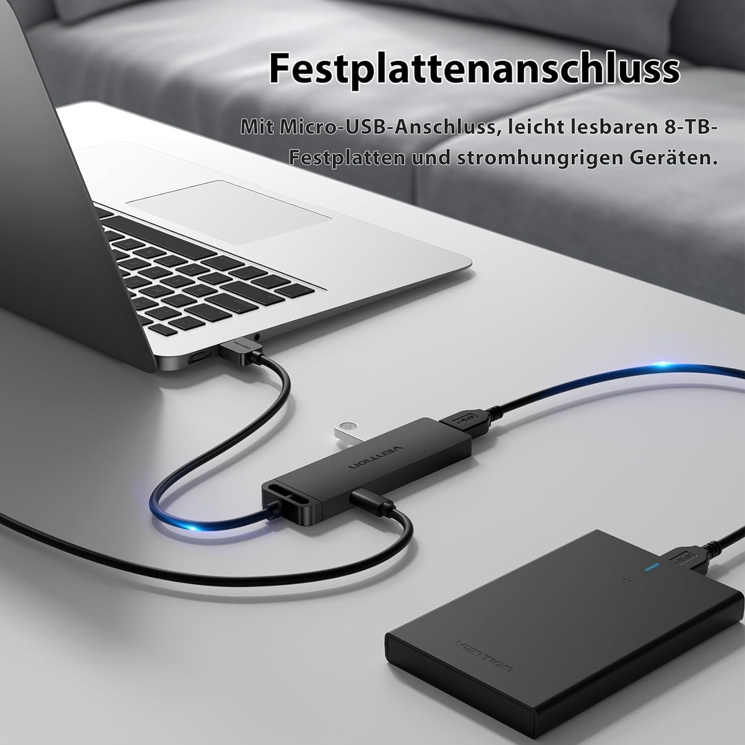 Laptop, angeschlossen an Hub und externe Festplatte. Weiße Oberfläche, schwarze Kabel.