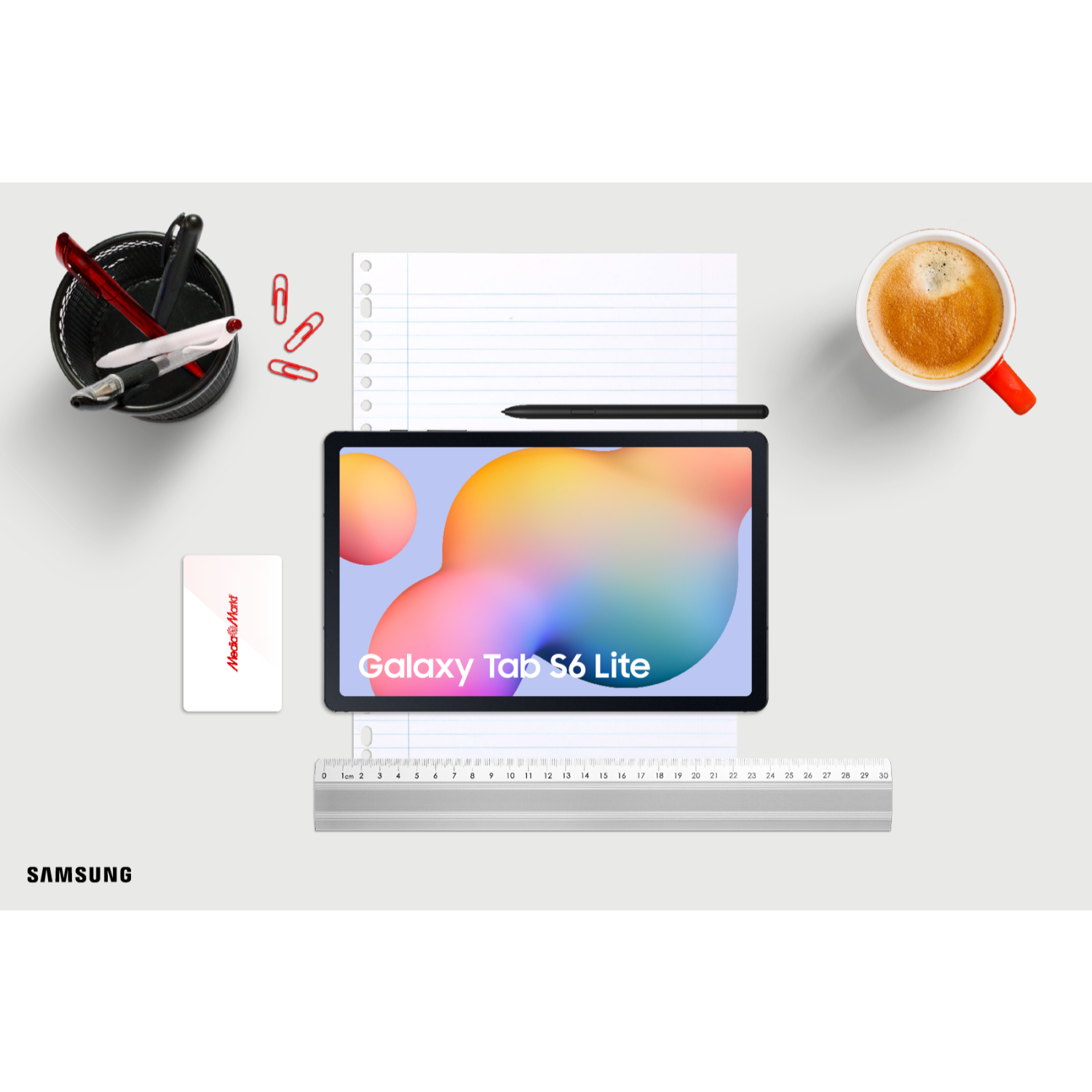 Ein Tablet, Stifte, ein Lineal, eine Karte, eine Kaffeetasse und Büroklammern liegen auf einer weißen Oberfläche. Das Tablet ist in der Mitte.
