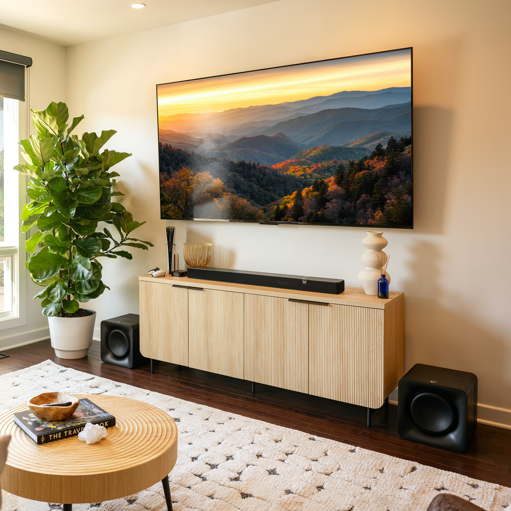 Soggiorno con una grande TV a parete, un mobile e un divano.