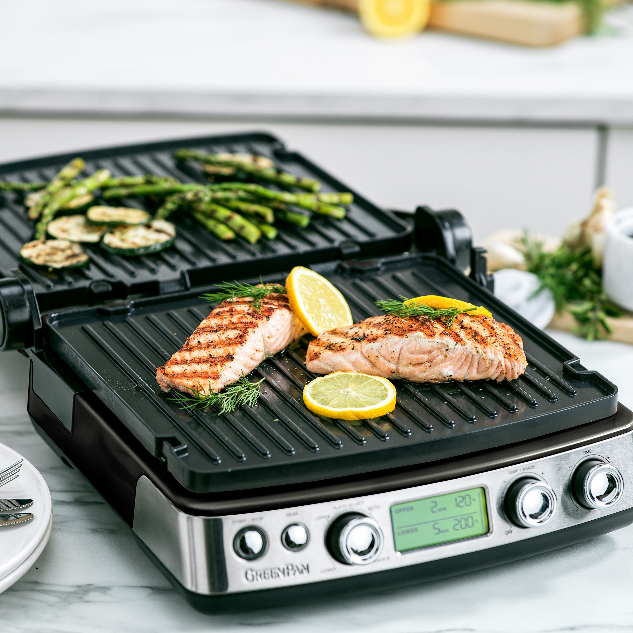 Ein Grill mit gegrilltem Lachs, Zitronenscheiben und Spargel. Der Grill steht auf einer Theke.