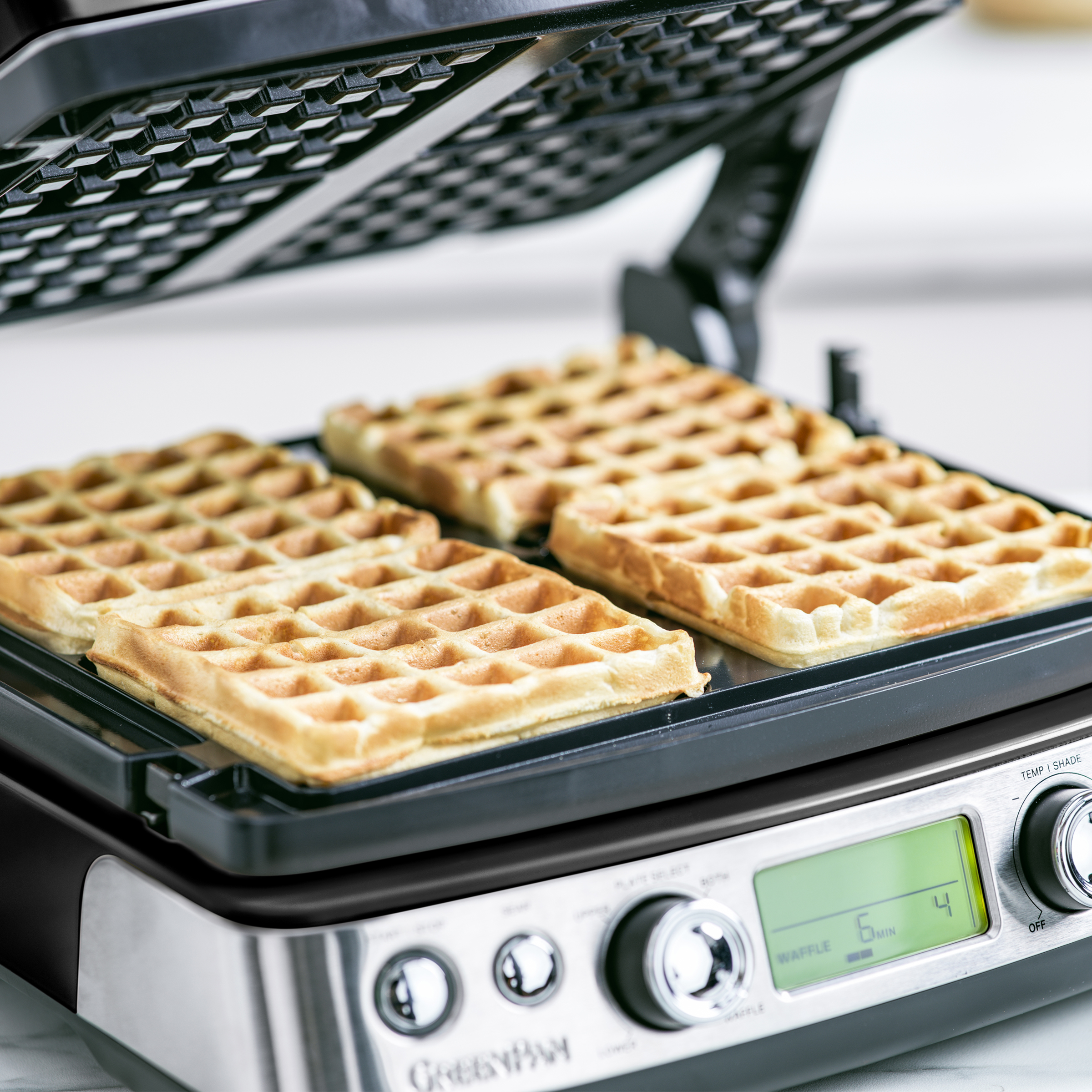 Ein Waffeleisen mit drei goldbraunen Waffeln. Das Bedienfeld ist rechts sichtbar.