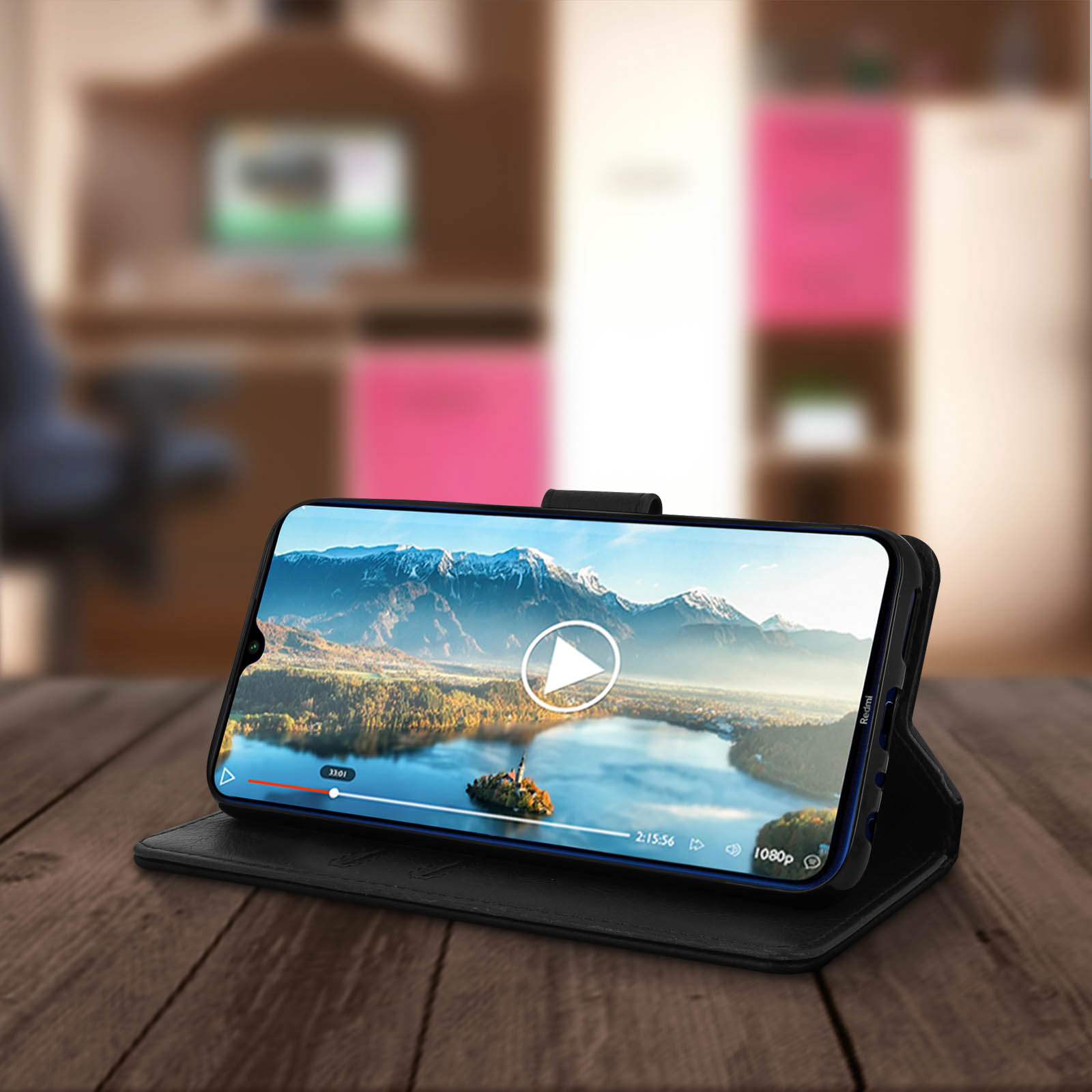 Un smartphone sur une table en bois affiche une vidéo. La vidéo montre une île avec un bouton de lecture.