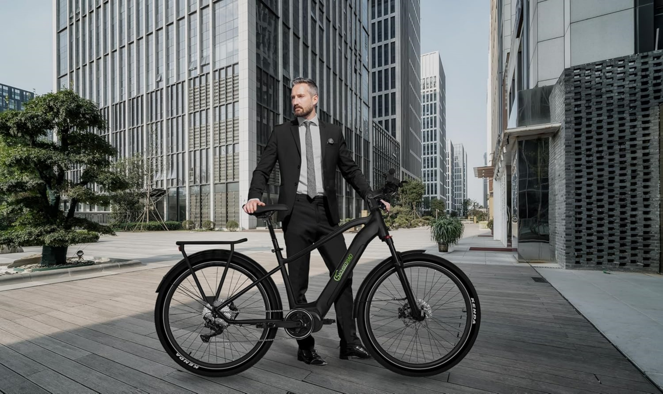 Ein Mann im Anzug steht mit einem Elektrofahrrad auf einer Stadtstraße.