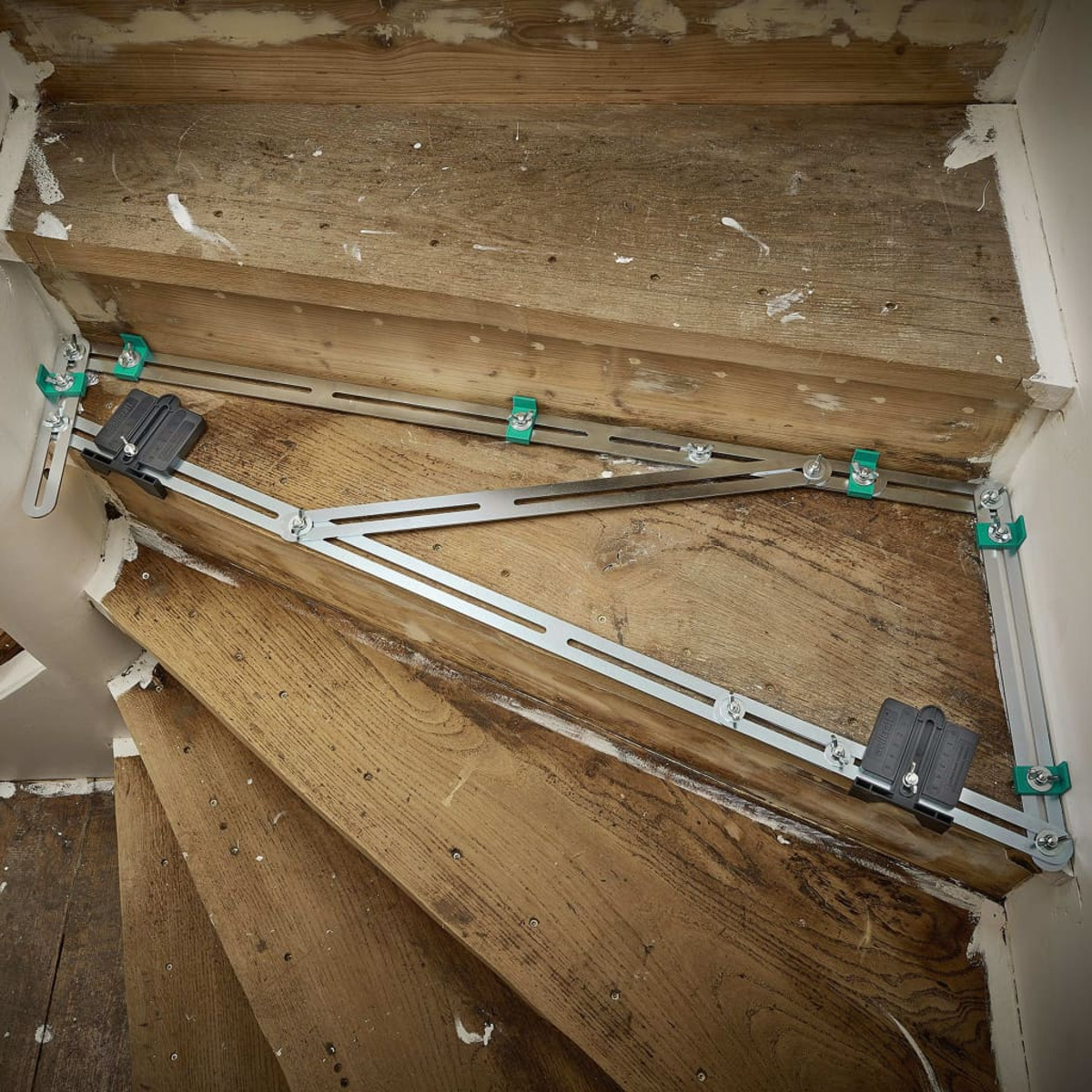 Ristrutturazione della scala in corso. Gradini in legno, staffe metalliche argentate, fissaggi verdi.