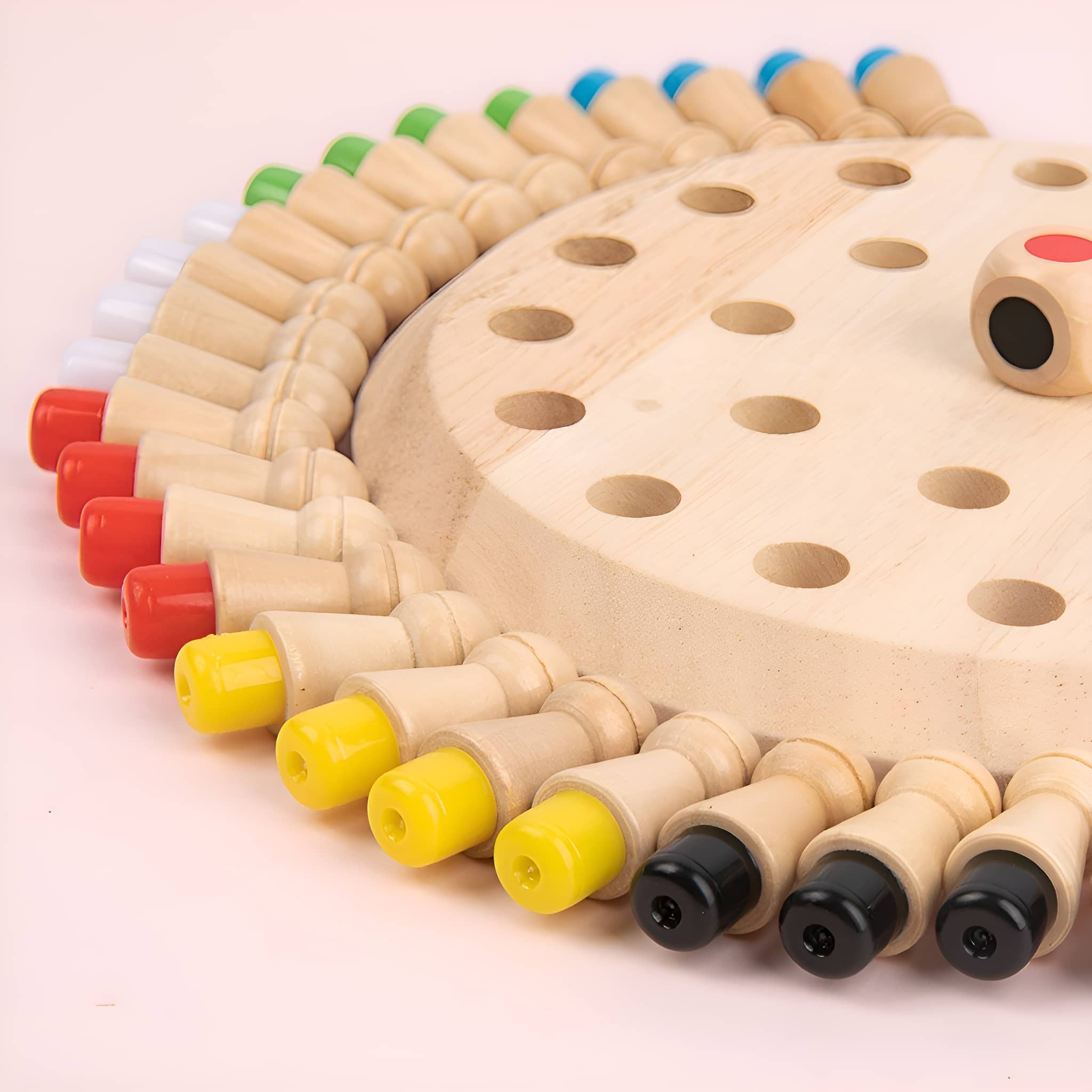 Holzbrettspiel mit bunten Stiften und einem Würfel. Rosa Hintergrund. Stifte: gelb, rot, grün, weiß, schwarz, blau.