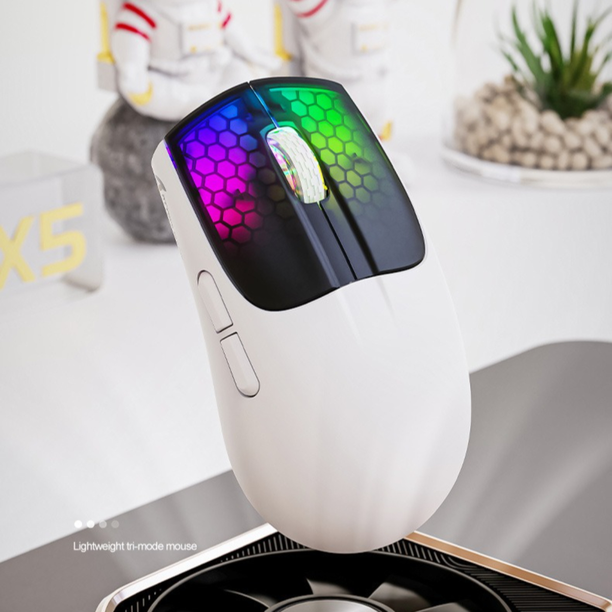 Eine weiße Gaming-Maus mit bunten Lichtern. Die Maus liegt auf einer schwarzen Oberfläche.