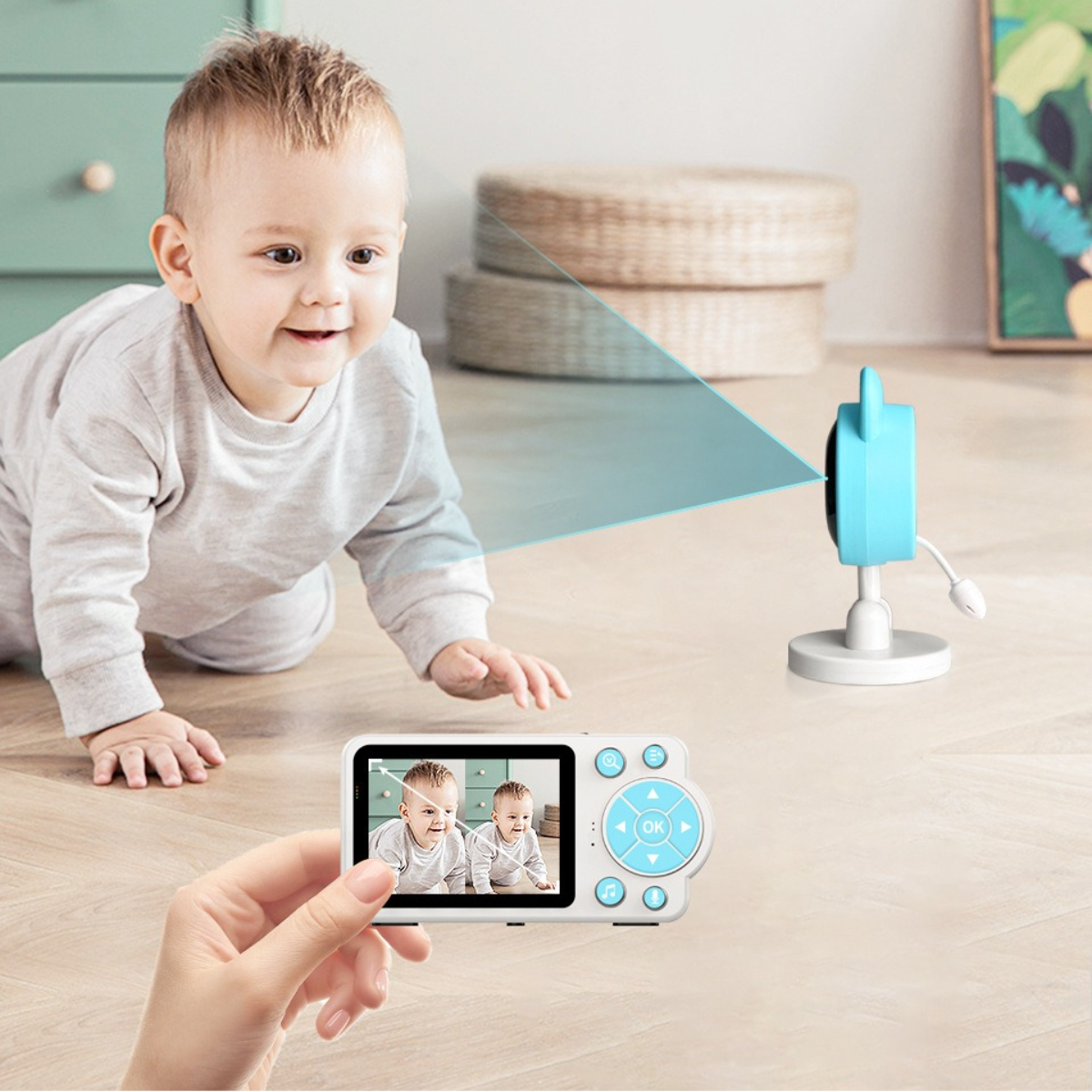Ein Baby betrachtet eine Kamera, deren Bildschirm ein Baby zeigt, und einen Babyphone.