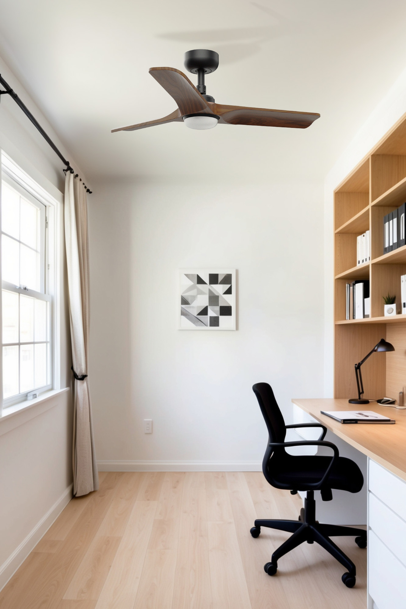Ein Heimbüro mit Deckenventilator, Kunst, Schreibtisch und Stuhl. Helle Holzböden und weiße Wände. Ein Fenster mit Vorhängen links.