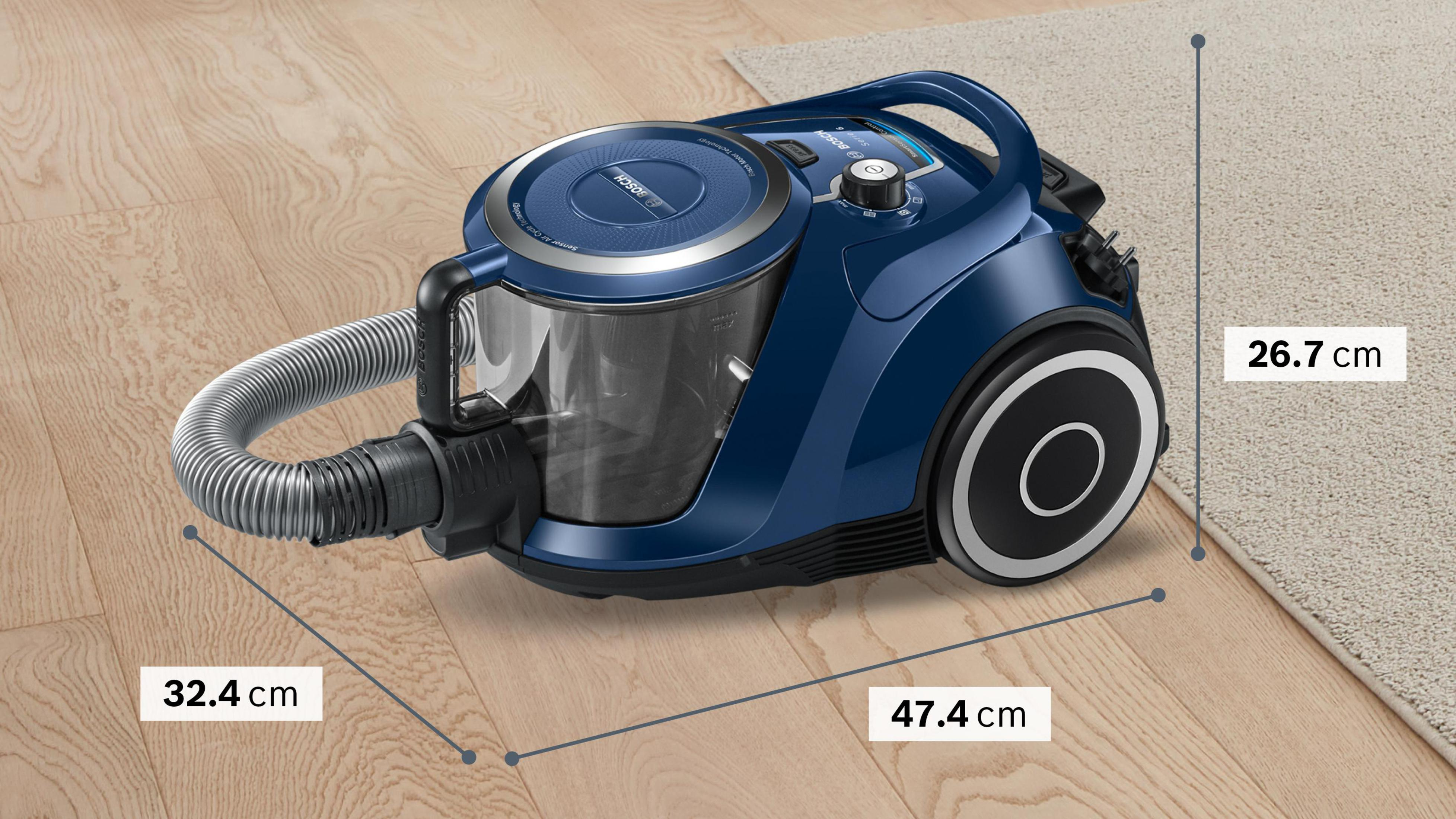 Niebieski odkurzacz na drewnianej podłodze, z wymiarami: 32,4 cm, 47,4 cm i 26,7 cm.