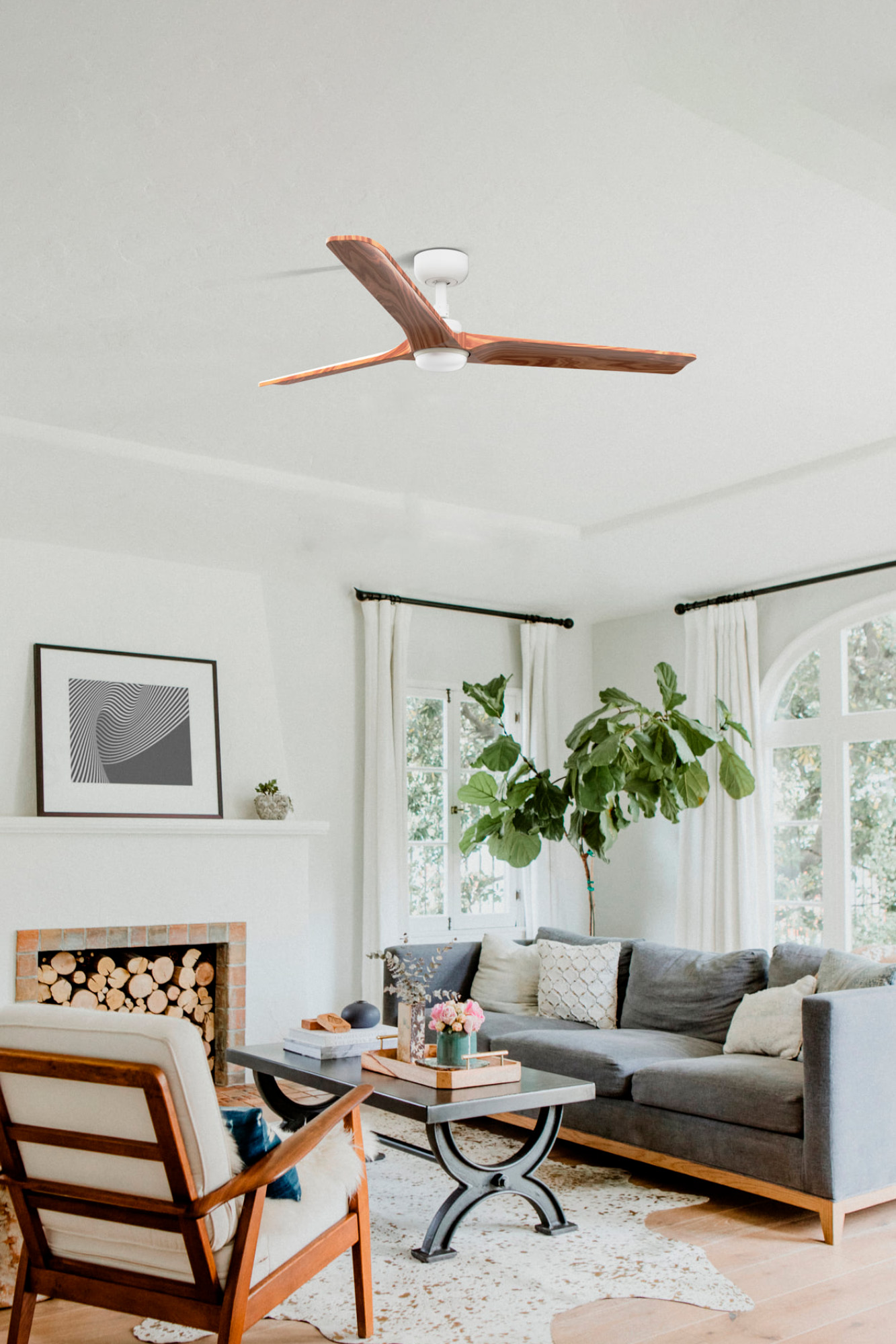Ein Wohnzimmer mit Deckenventilator, Sofa, Kamin und Kunstwerken. Der Raum ist gut beleuchtet und modern.