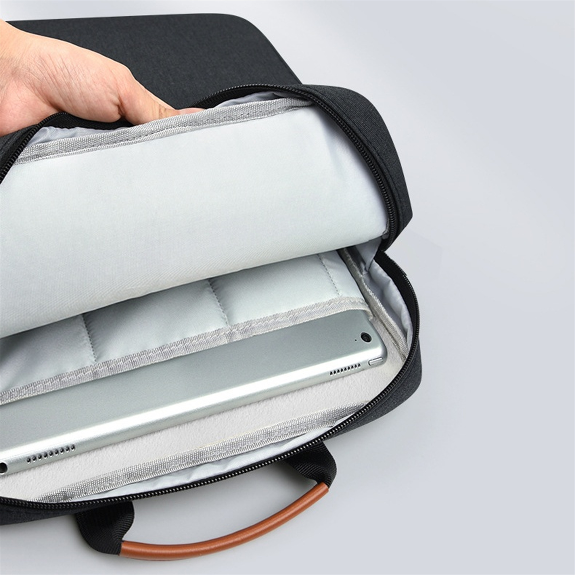 Laptop in einer schwarzen Tasche mit braunem Griff. Die Tasche ist geöffnet. Weißer Hintergrund.