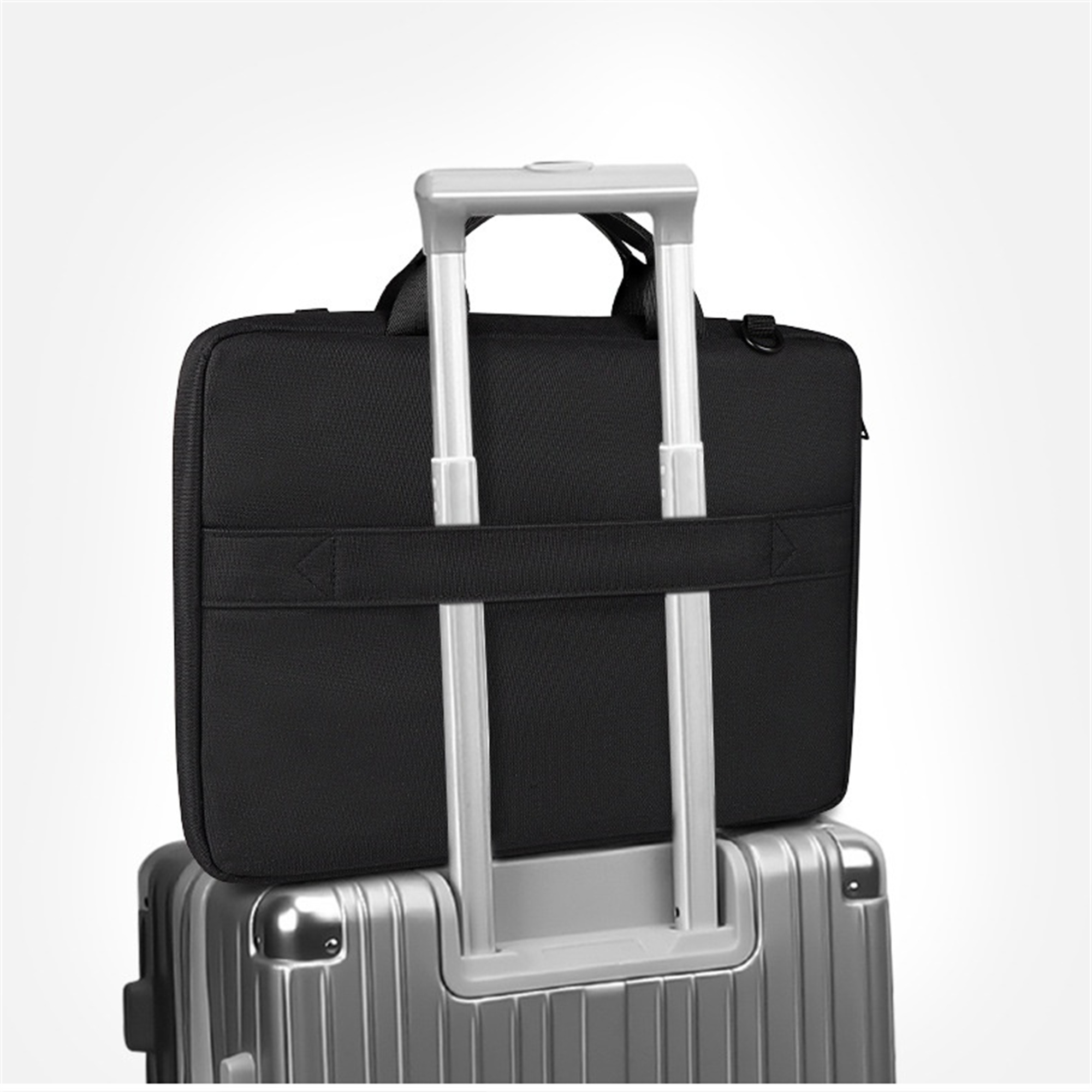 Eine schwarze Laptoptasche liegt auf einem silbernen Koffer mit Griff. Die Tasche ist zentriert.