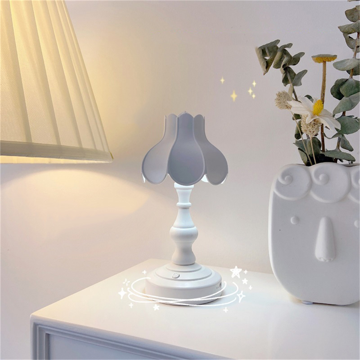 Eine weiße Lampe auf einem weißen Tisch mit einer weißen Vase.