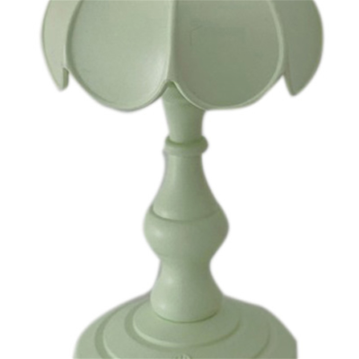 Eine hellgrüne Lampe, auf weißem Hintergrund, mit floralem Design.