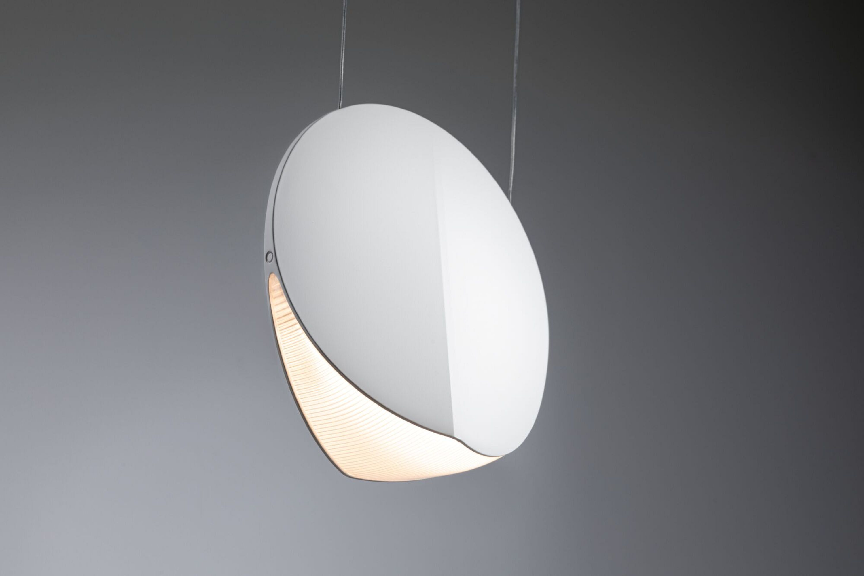 Eine moderne, weiße, eiförmige Lampe hängt an dünnen Drähten. Der Boden hat einen leuchtenden Schlitz.