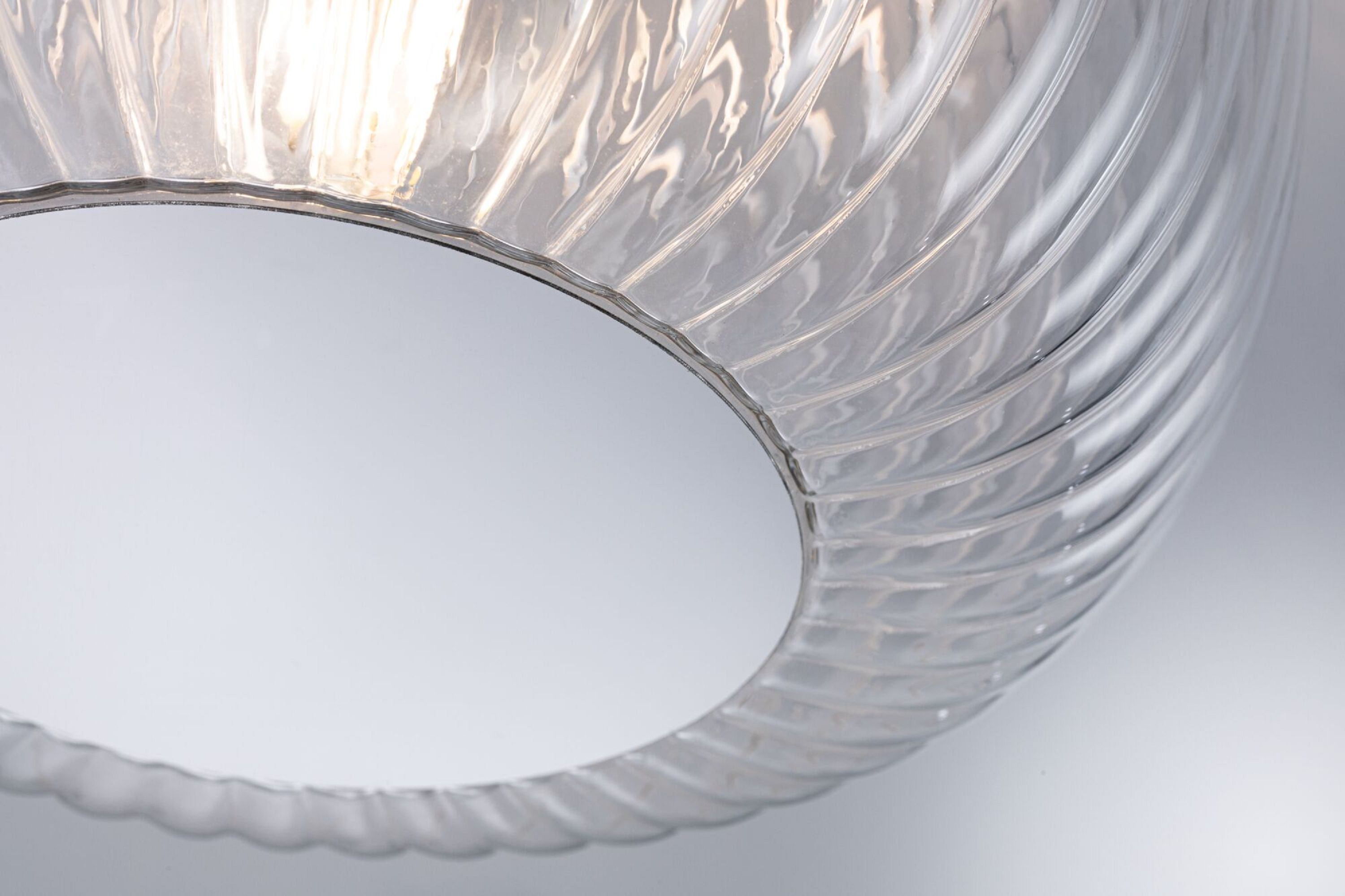 Zbliżenie przezroczystej szklanej żarówki. Szkło ma spiralny wzór.