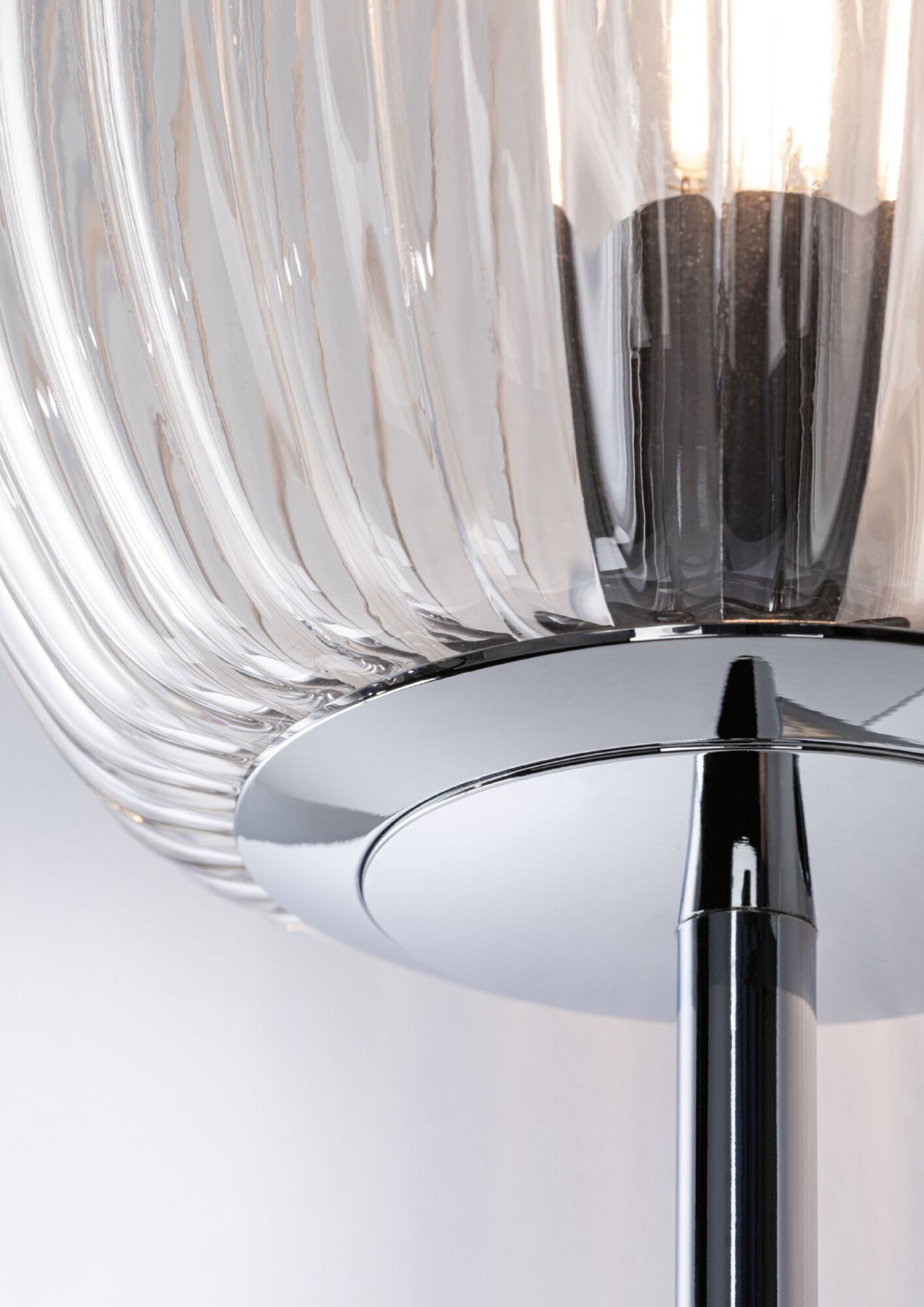 Nahaufnahme einer Lampe mit klarem, geripptem Glasschirm und Chromfuß.
